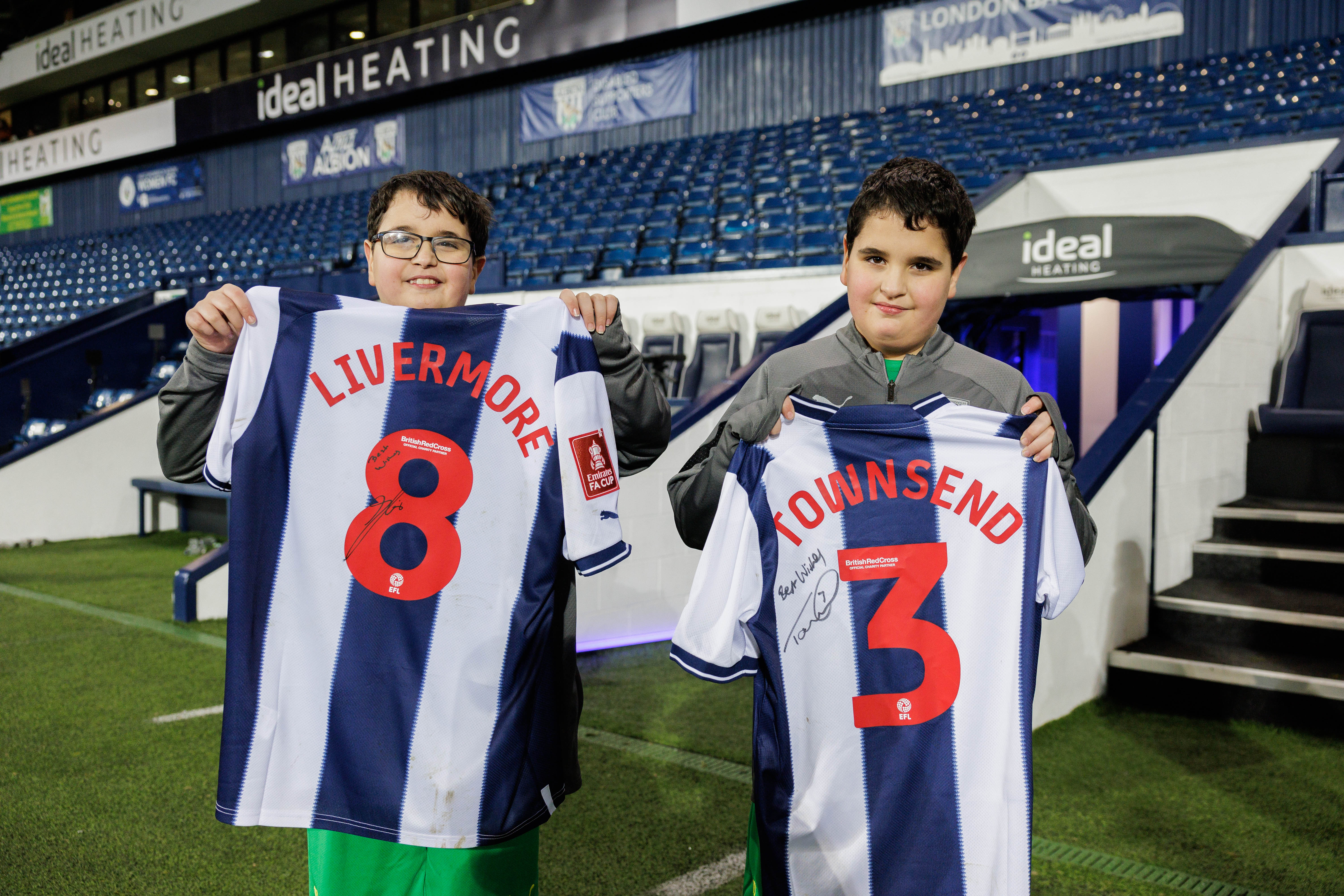 James & Richard holding shirts signed by Livermore & Townsend 