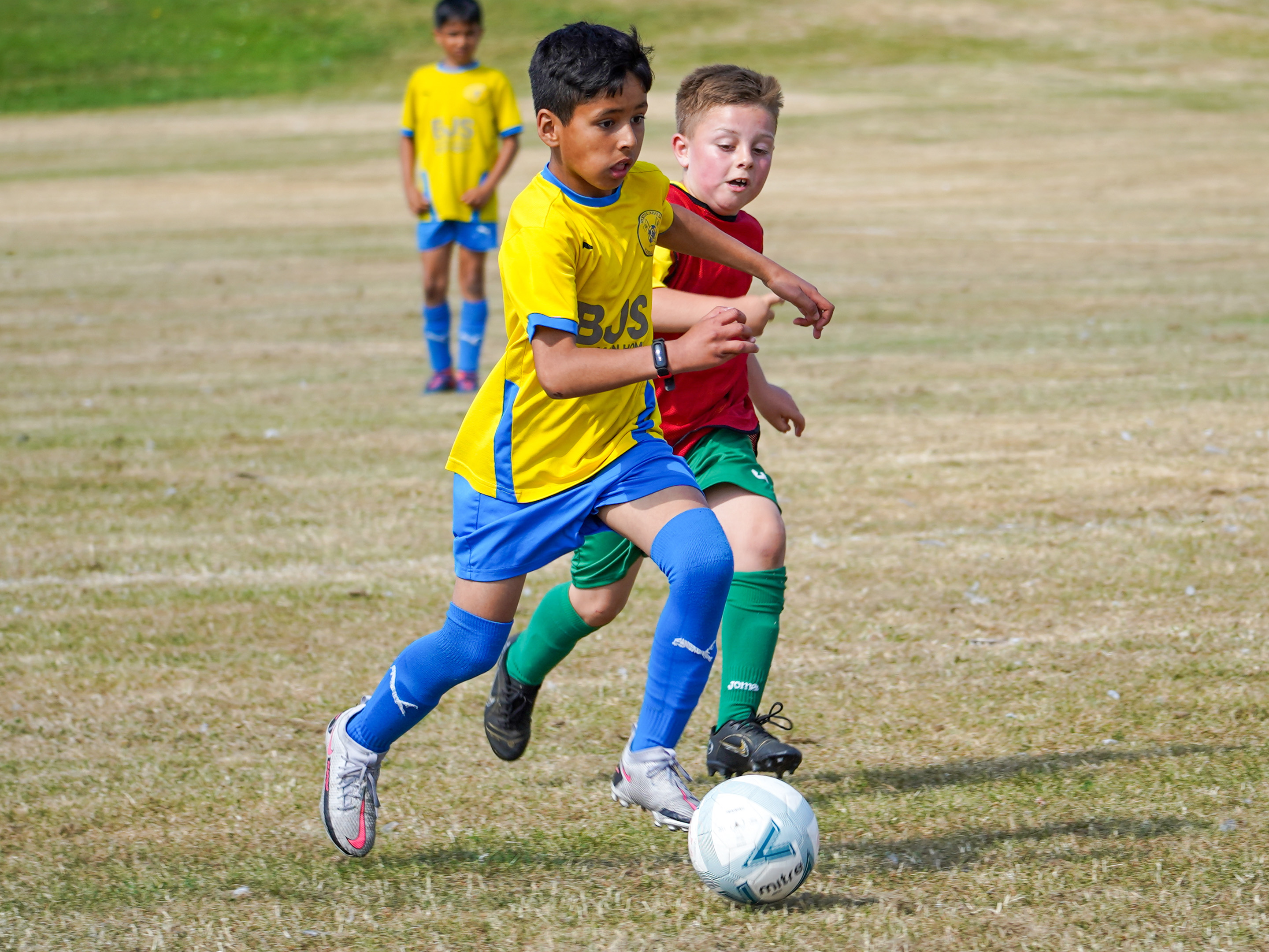 Grassroots players running with football at his feet.