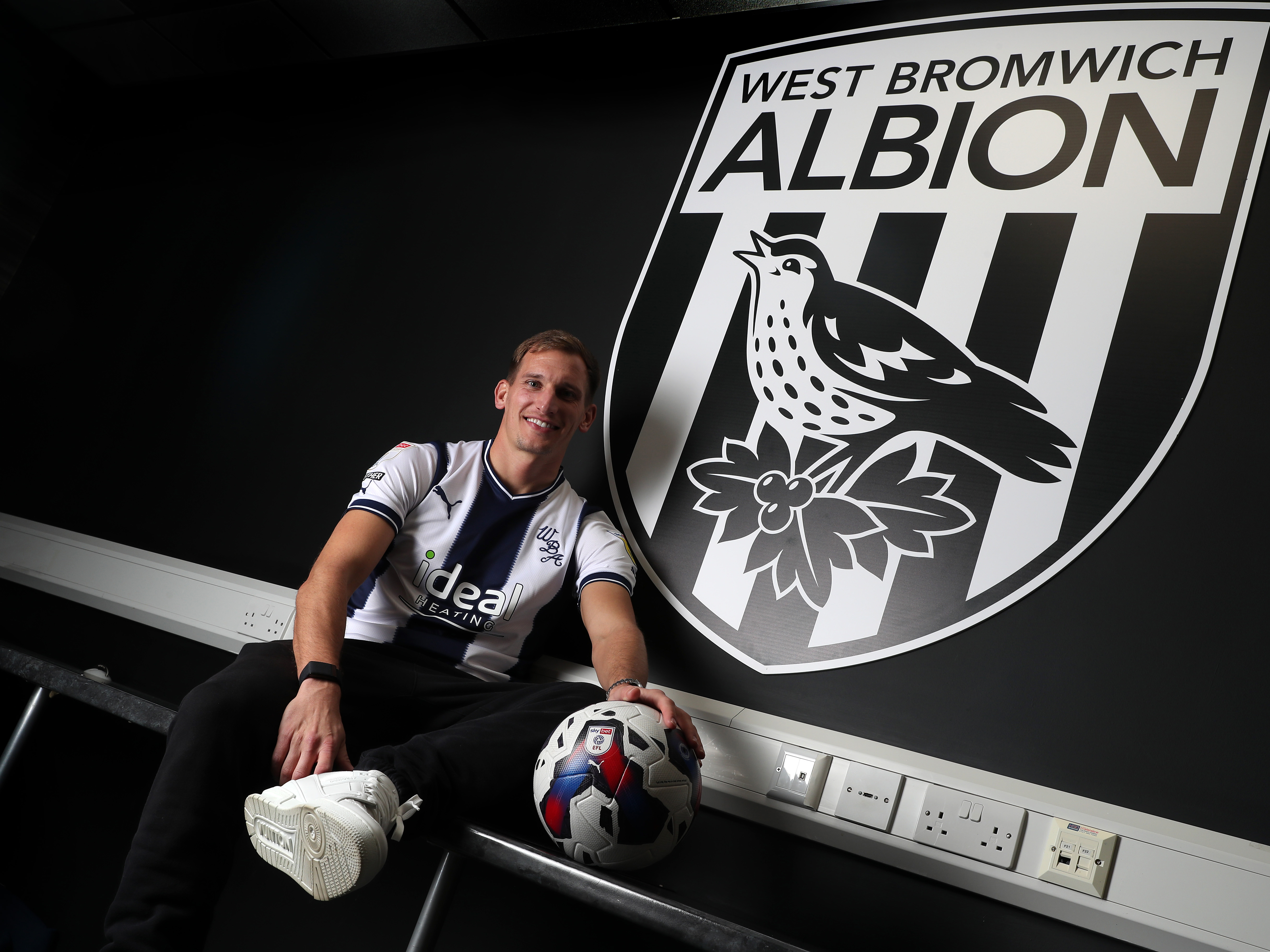 An image of Marc Albrighton posing next to an Albion badge