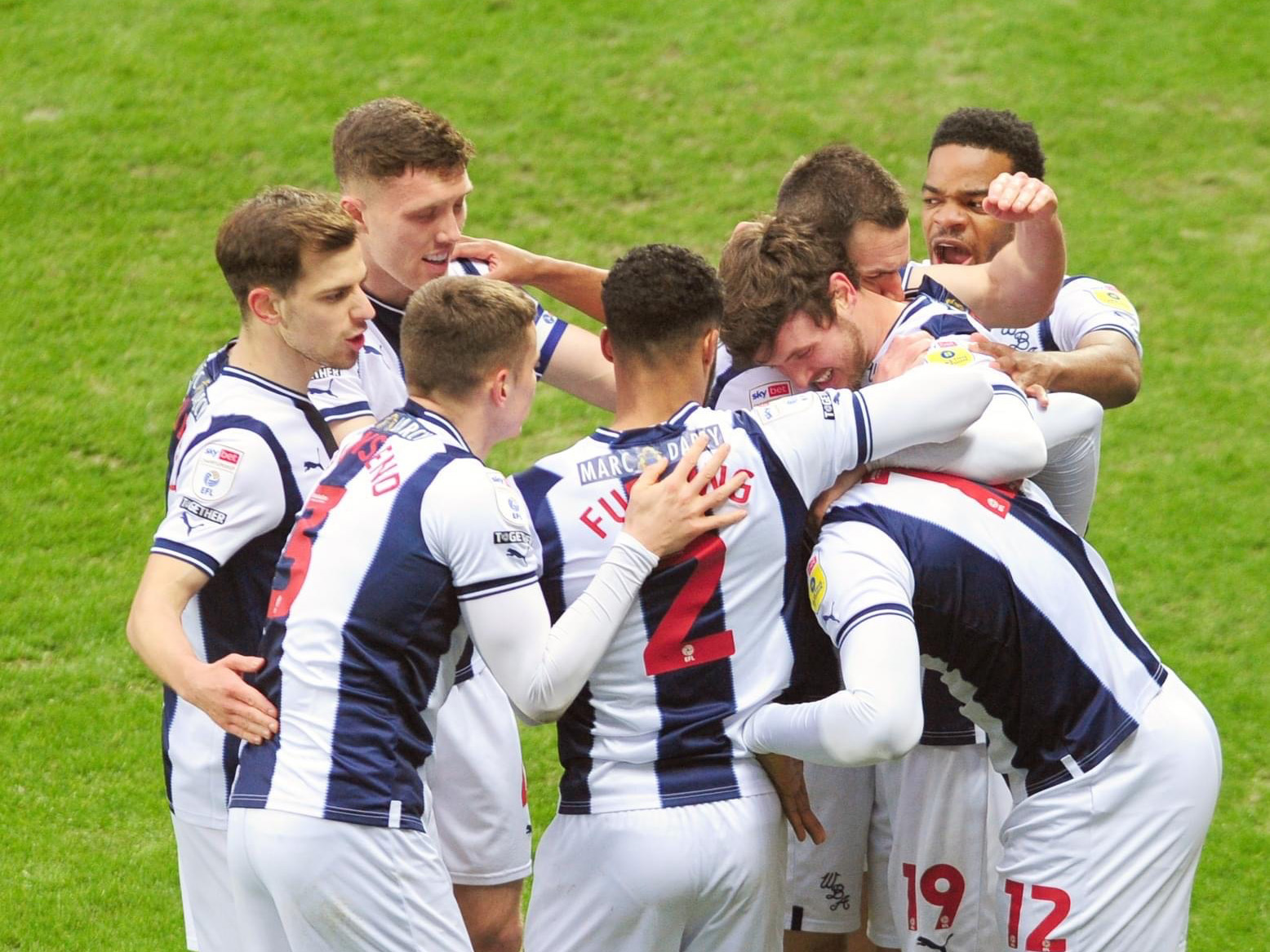 Albion players huddle together to celebrate scoring a goal