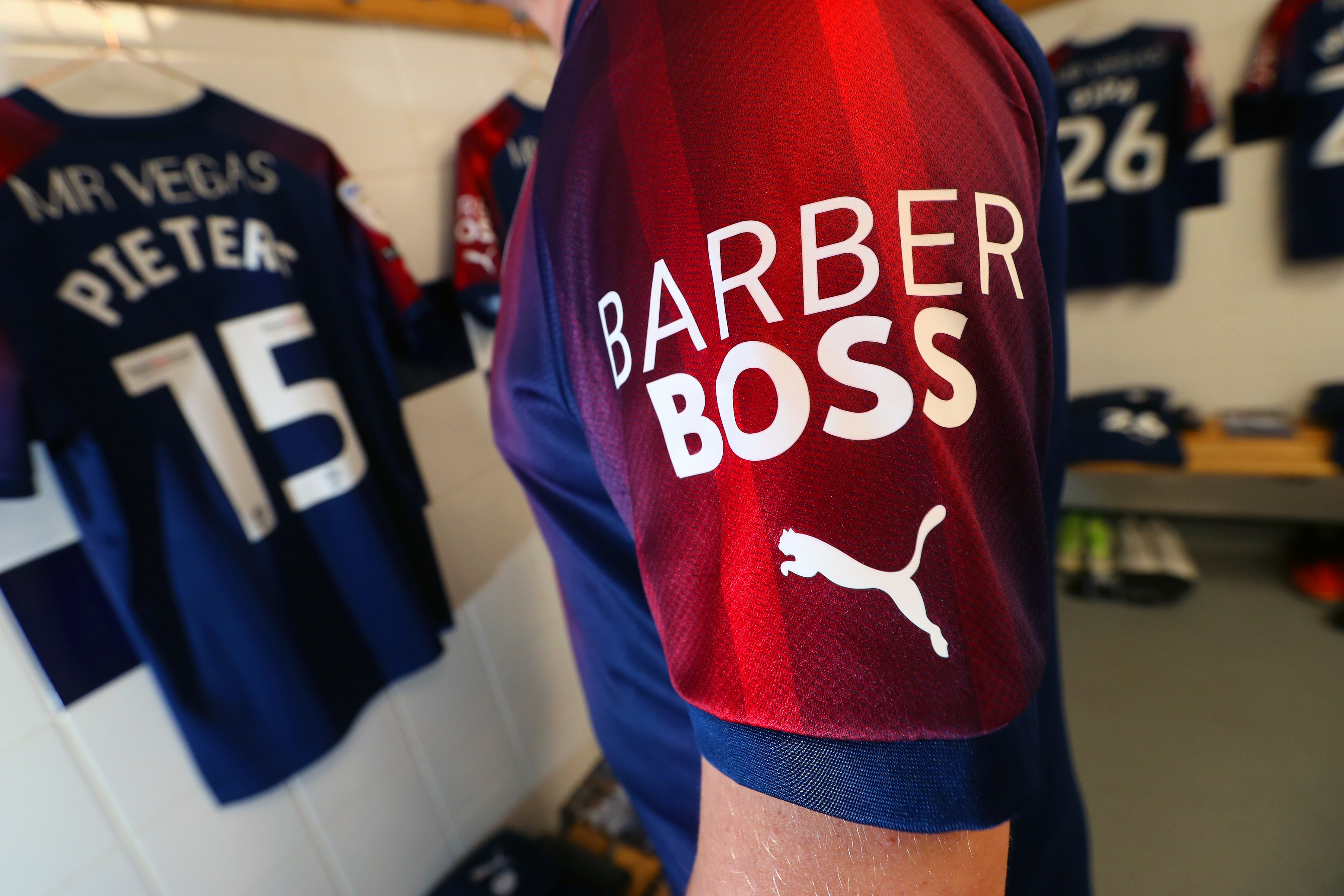 The Barber Boss logo on the sleeve of an Albion shirt.