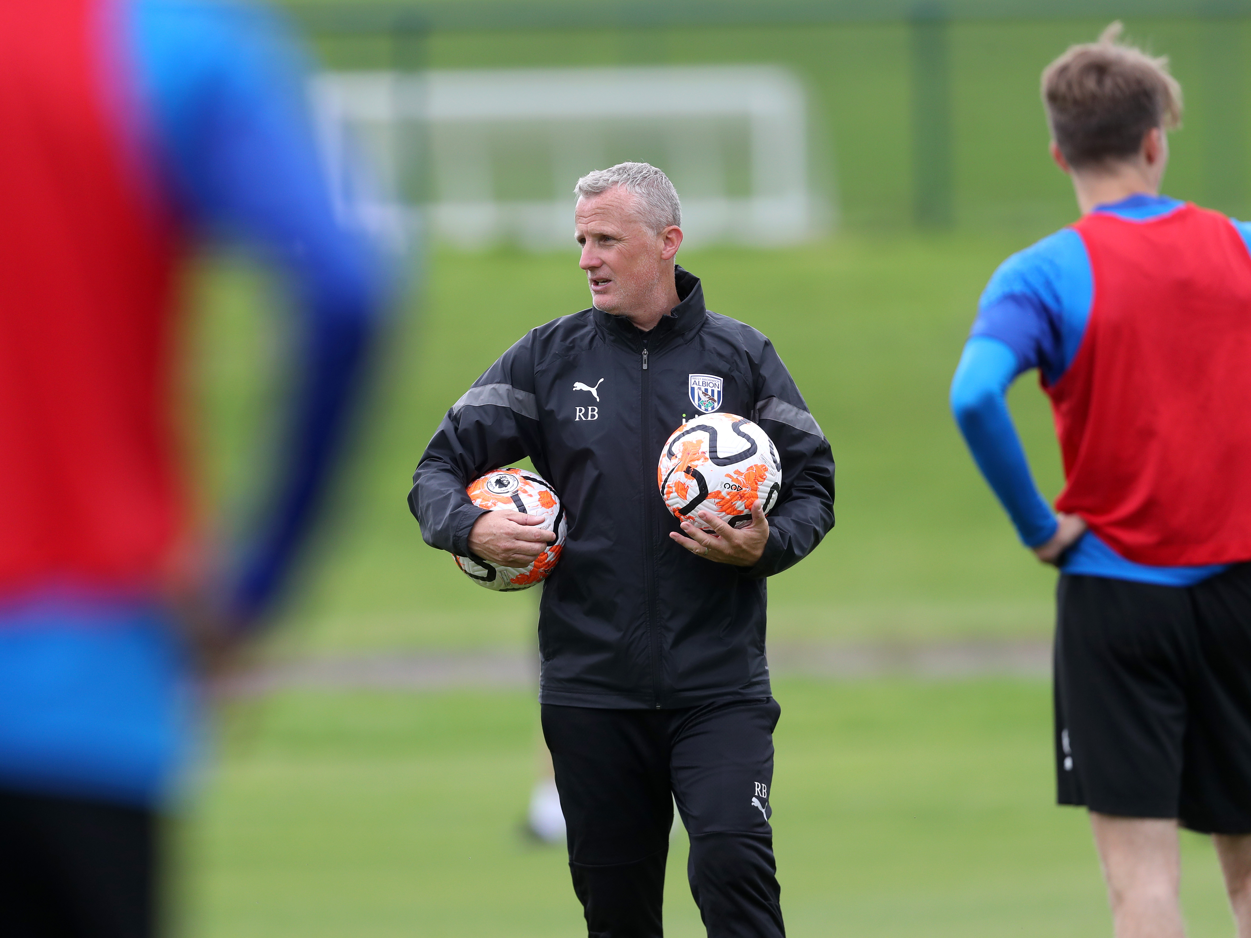 A photo of Under-21s boss Richard Beale holding two footballs while handing out instructions to Albion's academy prospects in training on the pitch