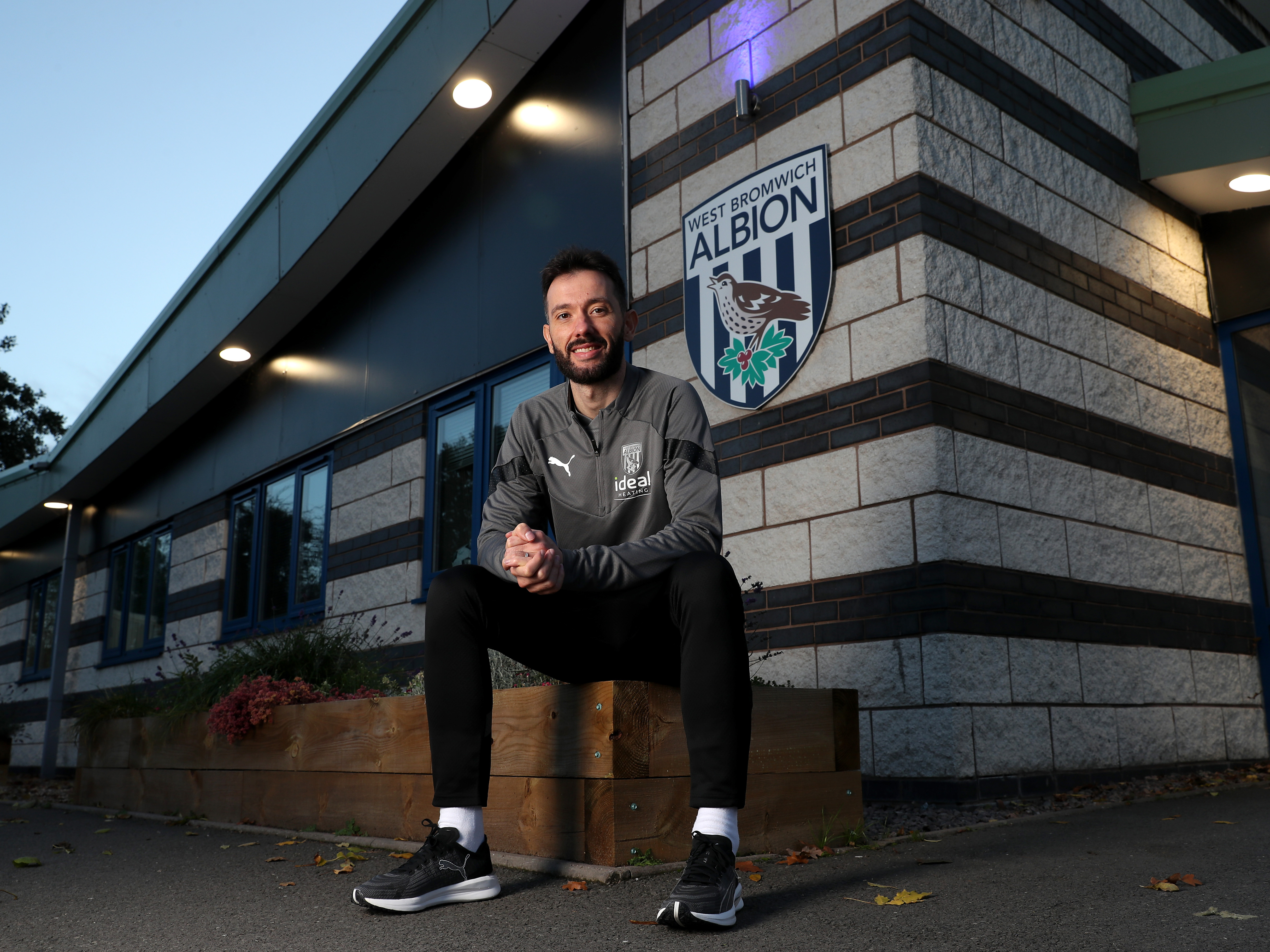Carlos Corberan sat down smiling at the camera outside Albion's training ground