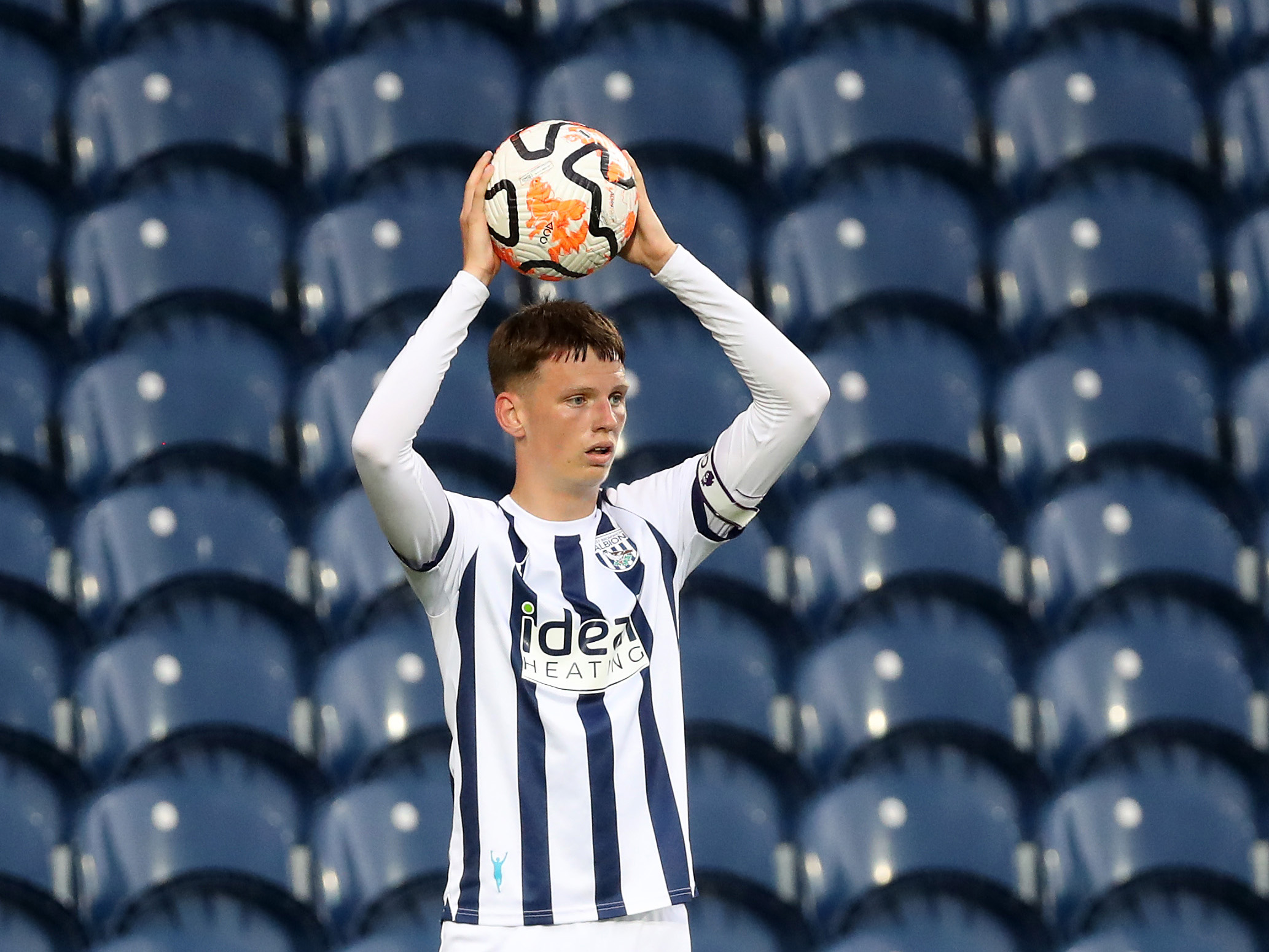 A photo of Albion academy graduate Reece Hall, in the 2023/24 home kit, taking a throw-in at The Hawthorns during Albion's PL2 game v Blackburn Rovers