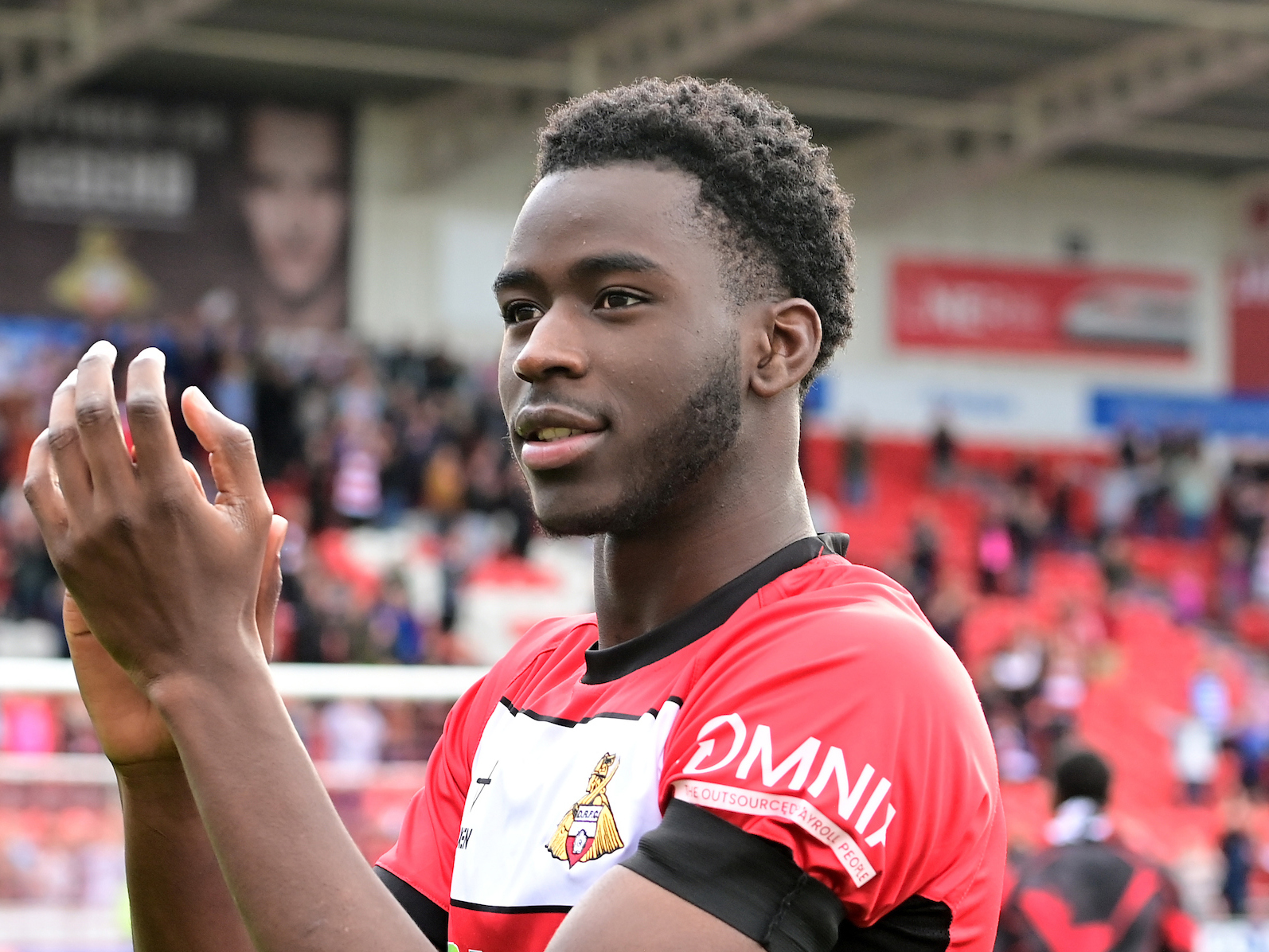 A photo of Albion academy graduate Mo Faal, applauding Doncaster fans in their home kit, following a game during his loan spell in South Yorkshire during the 2023/24 season