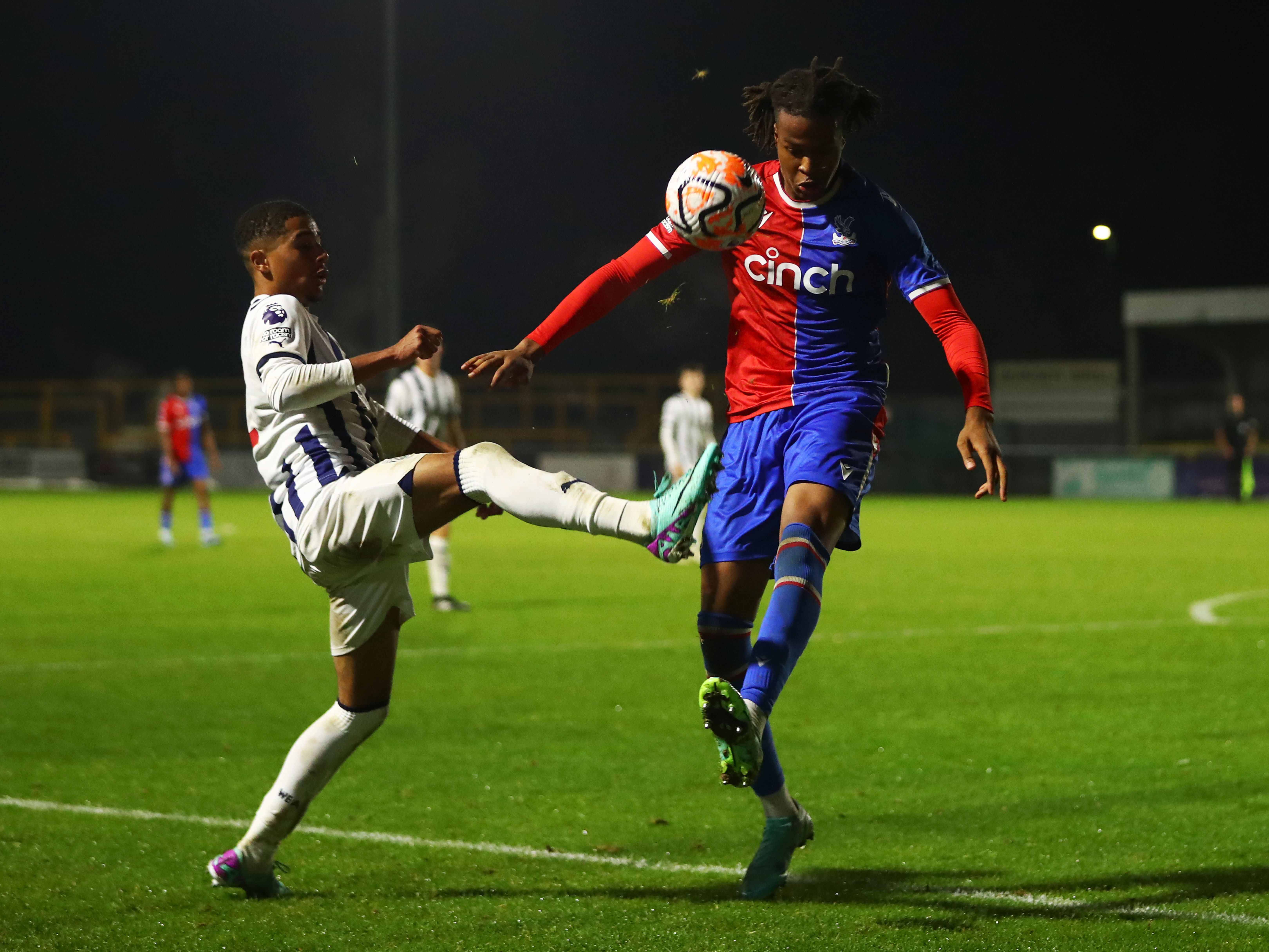 A photo of Albion U18s defender Deago Nelson, in the 2023/24 home colours, battling for the ball with a Crystal Palace player during a Premier League 2 game