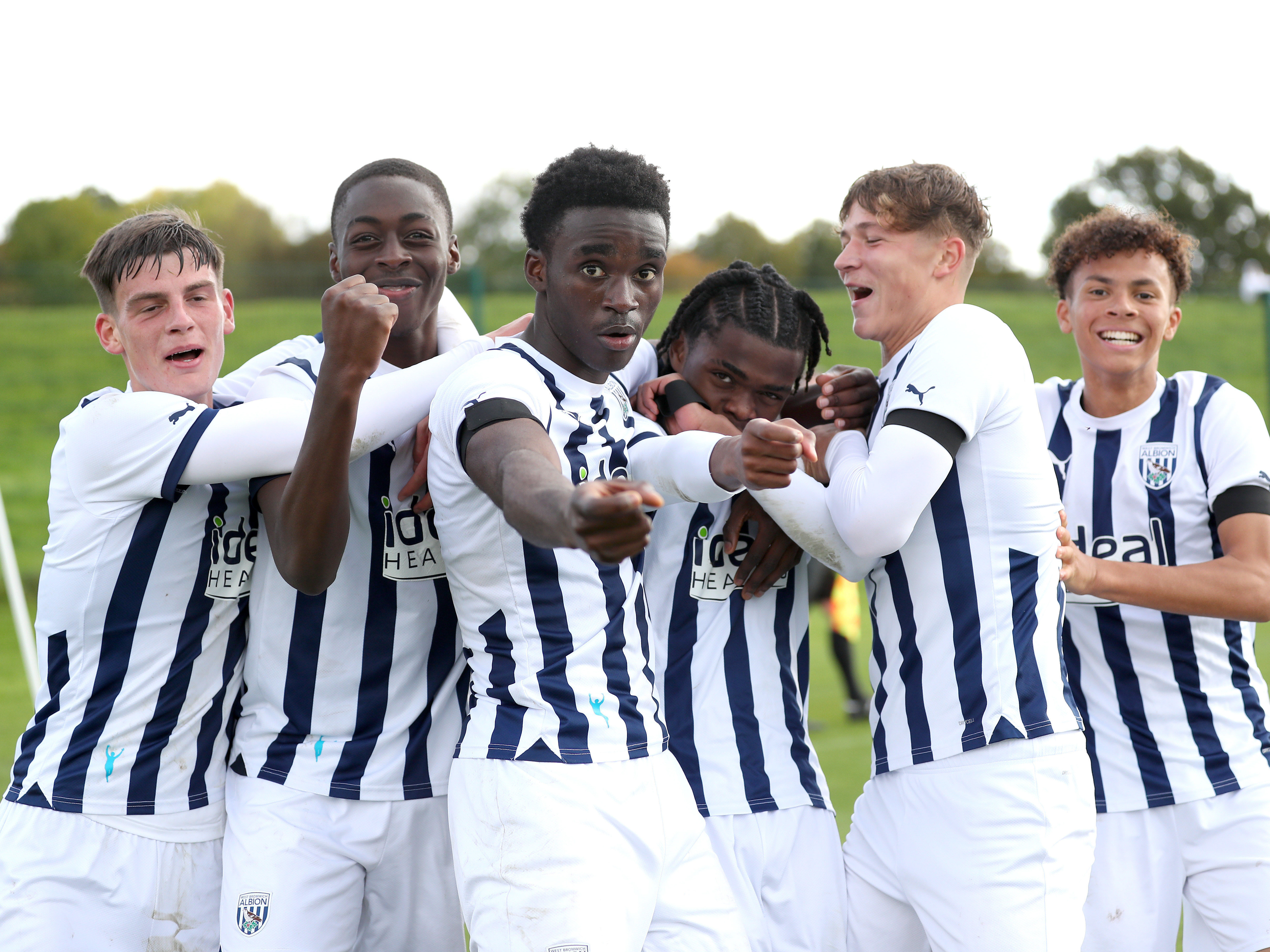 Albion Under 18s players, in the 2023/24 home kit, celebrate scoring straight down the camera in their match against West Ham at Albion's training ground