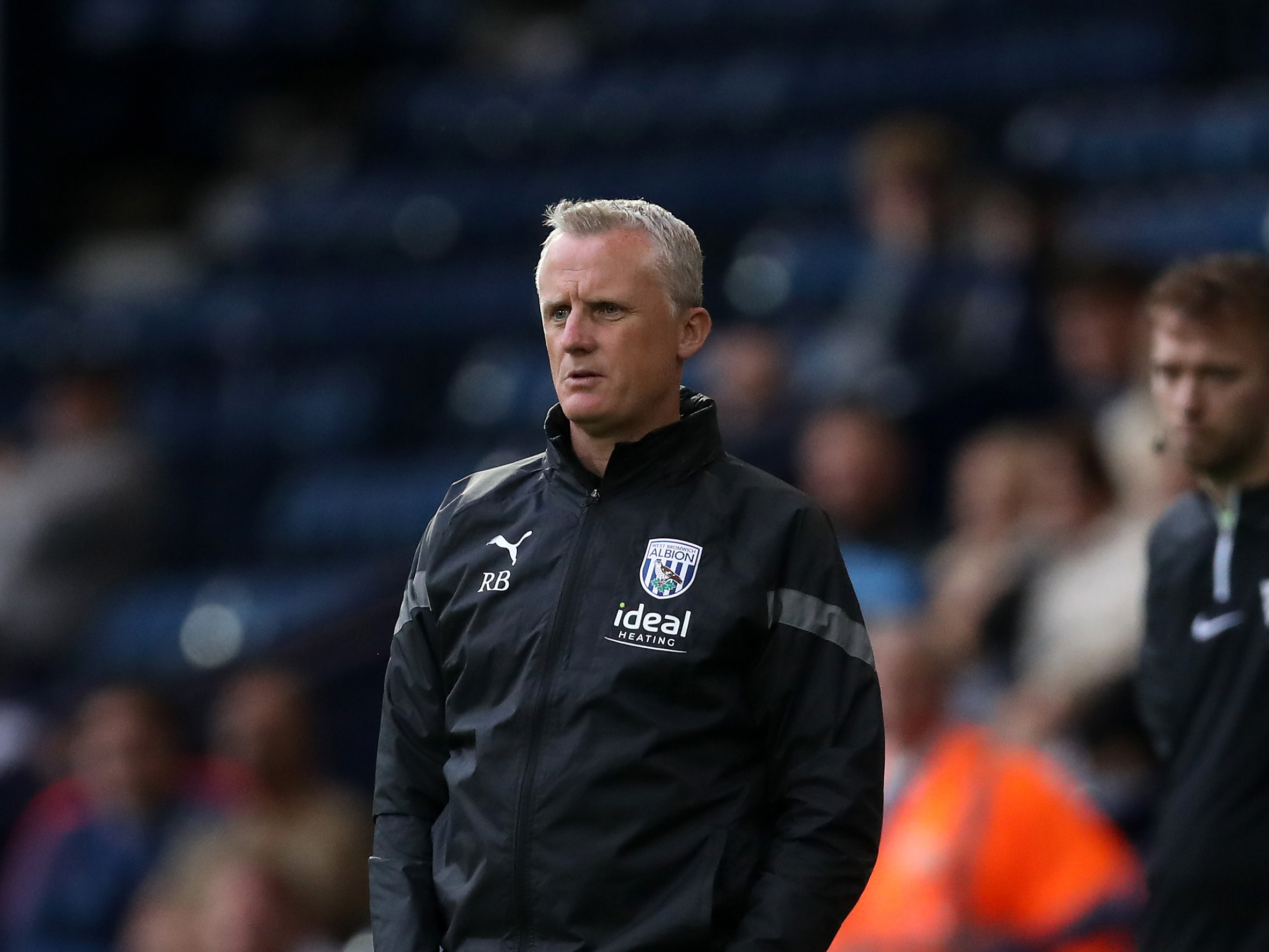 A photo of Albion U21s boss Richard Beale, in black tracksuit 2023/24 wear, looking on from The Hawthorns dugout