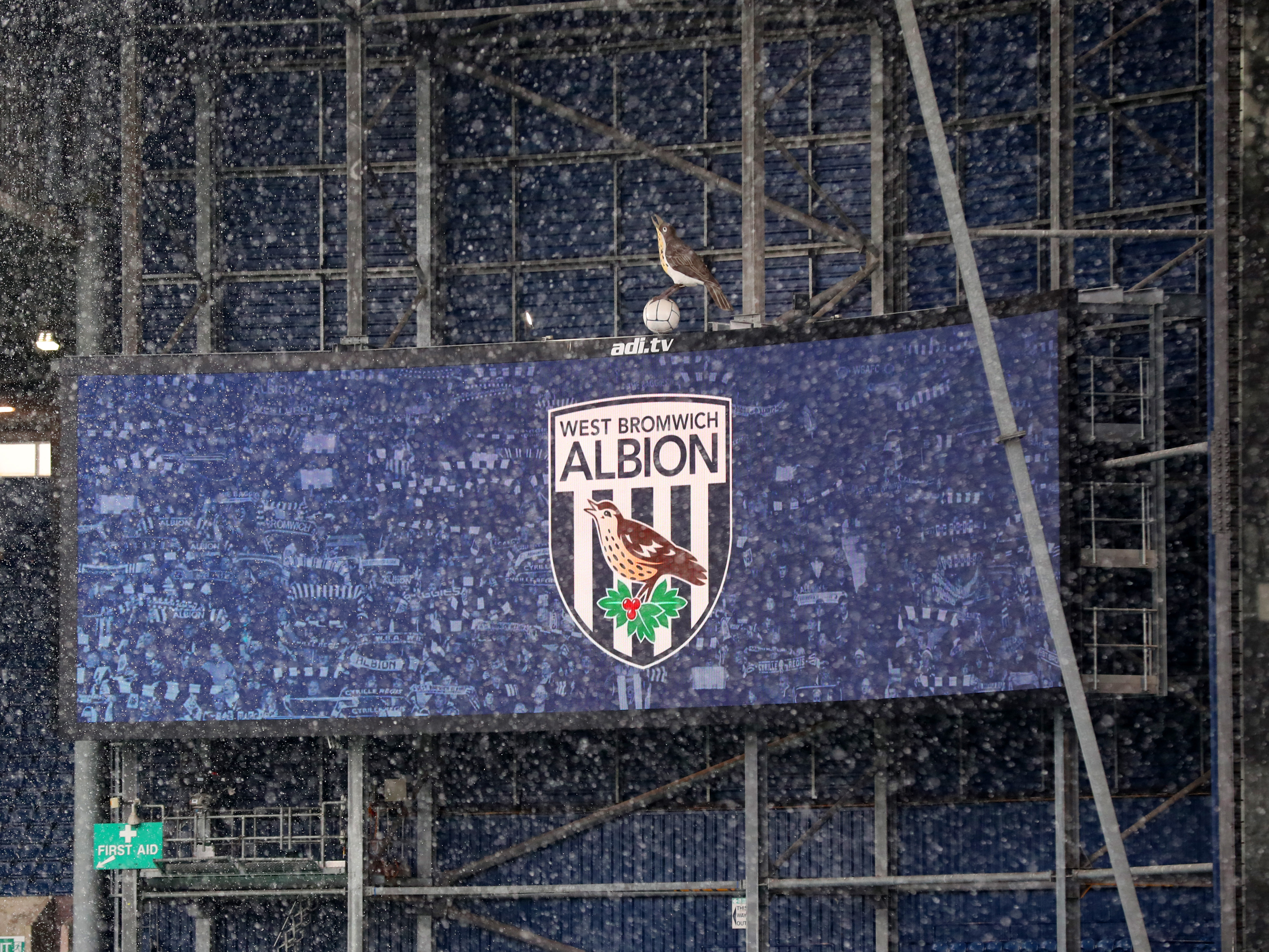 snow falling at The Hawthorns in front of an image of the big screen at the stadium