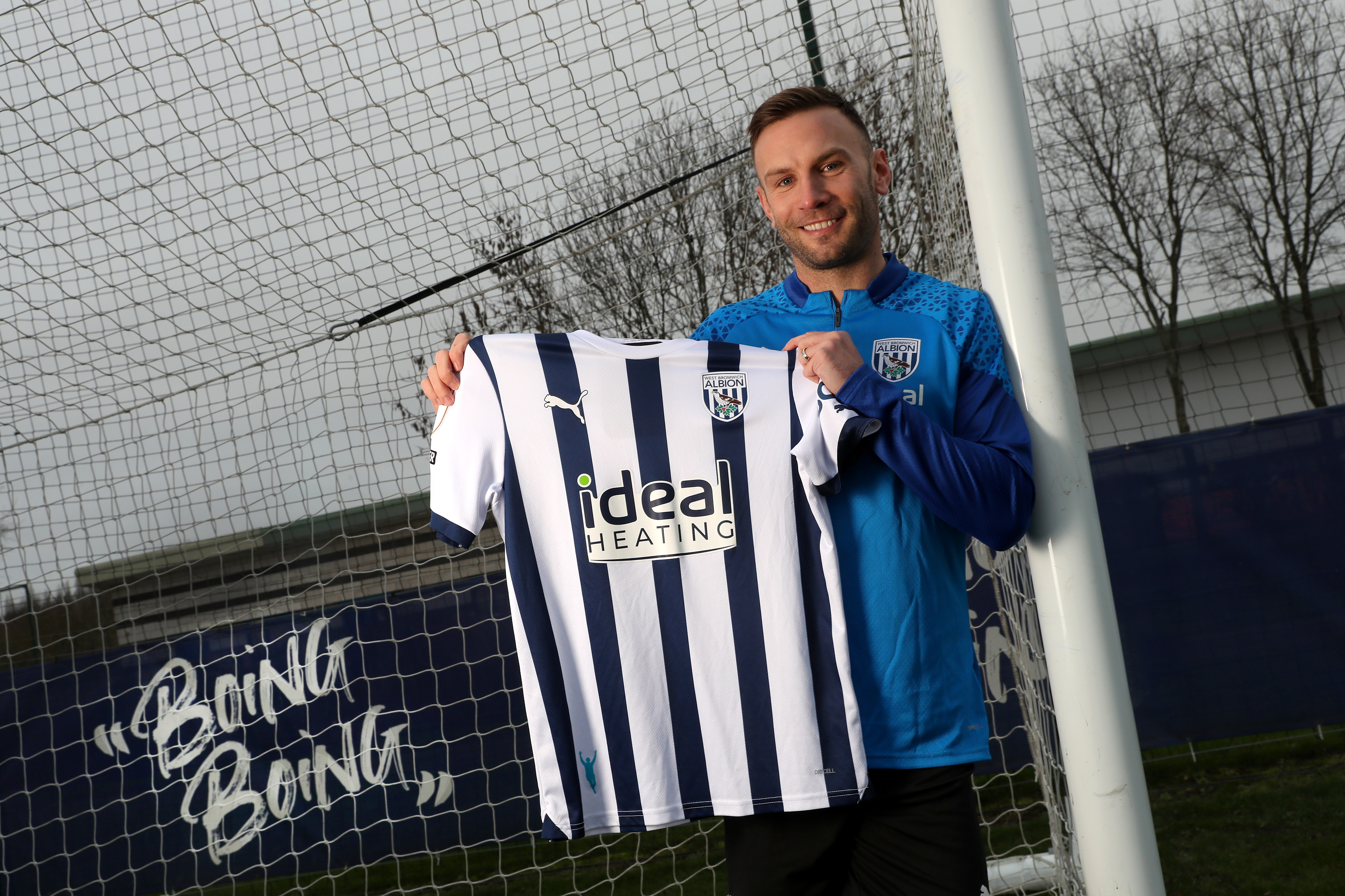 Andi Weimann smiling while holding up an Albion shirt