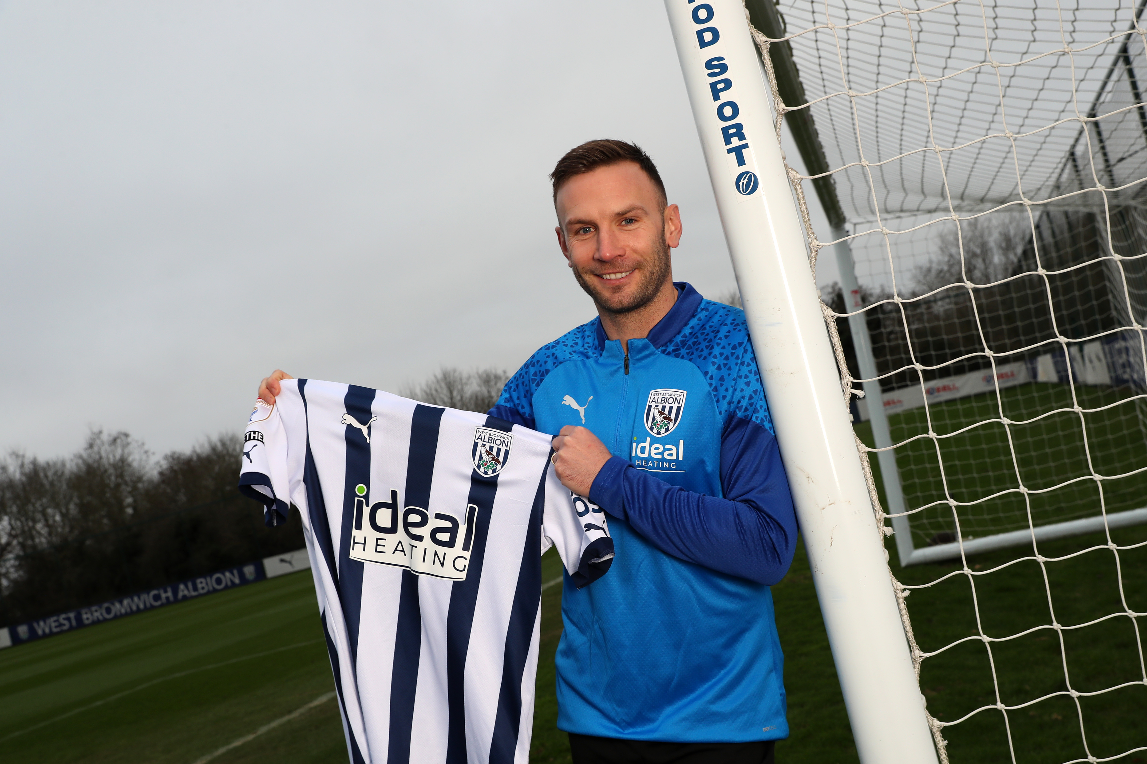 Andi Weimann smiling while holding up an Albion shirt