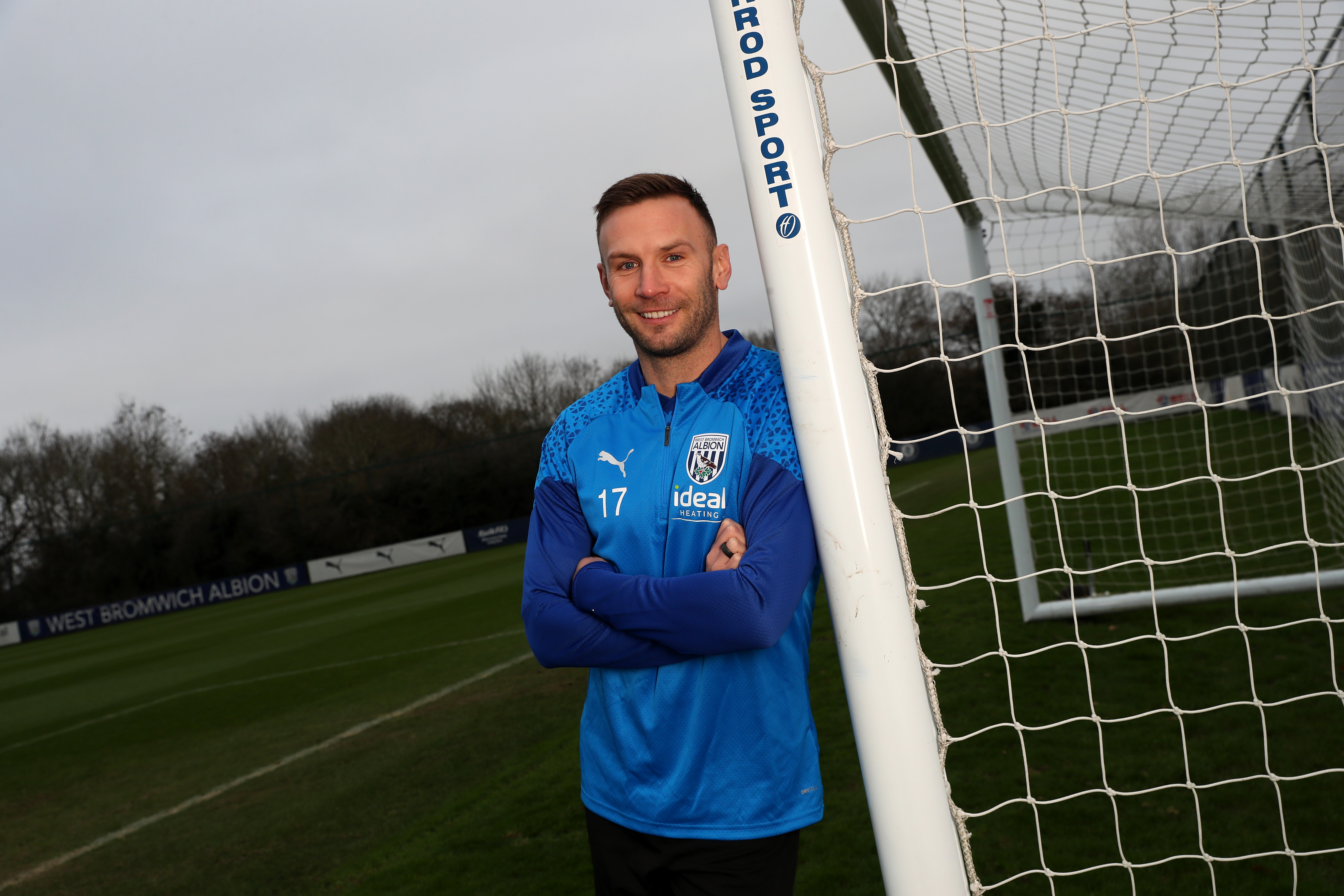 Andi Weimann smiling at the camera while leaning against a goal post
