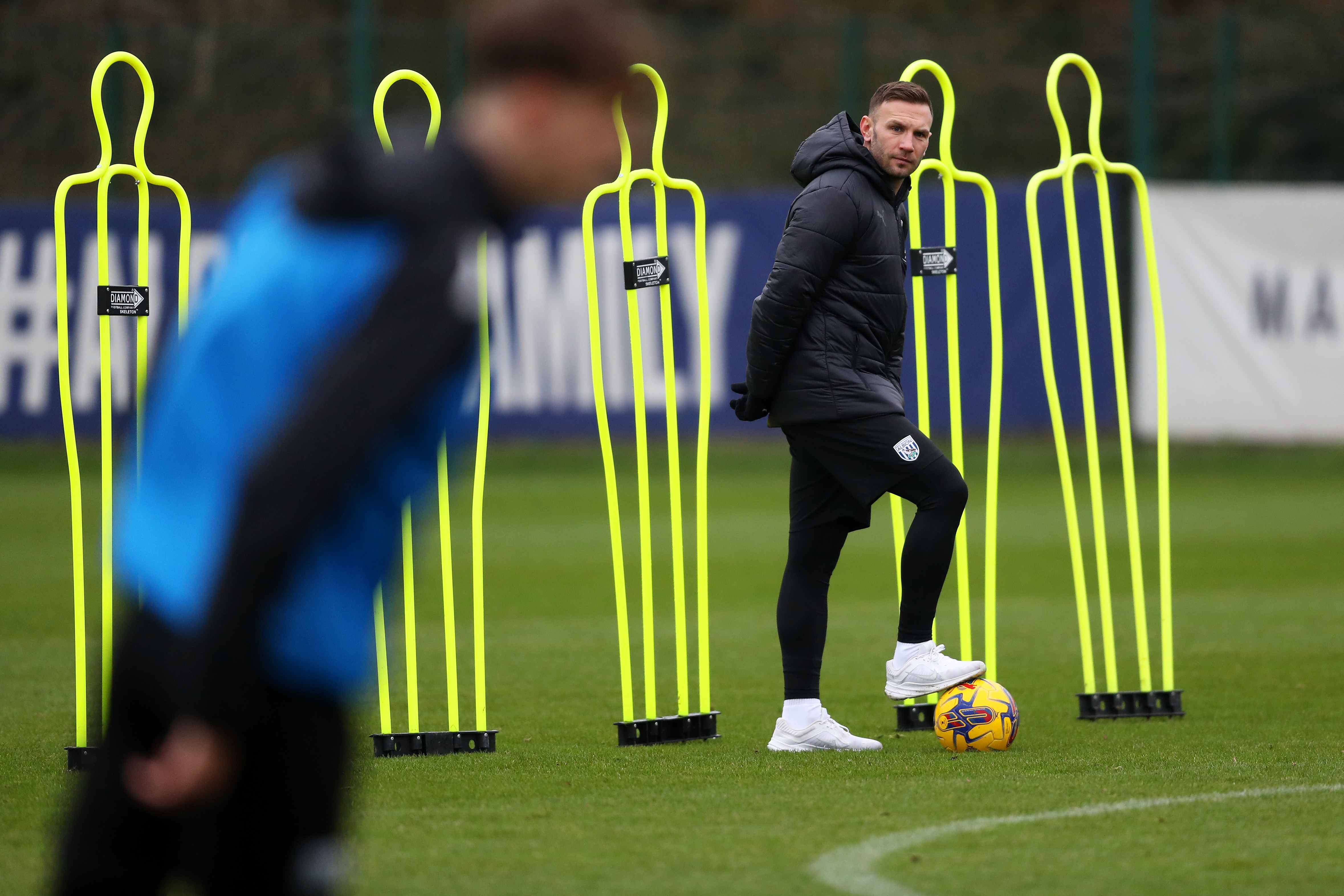 Andi Weimann watching training in a black coat while stood on a ball
