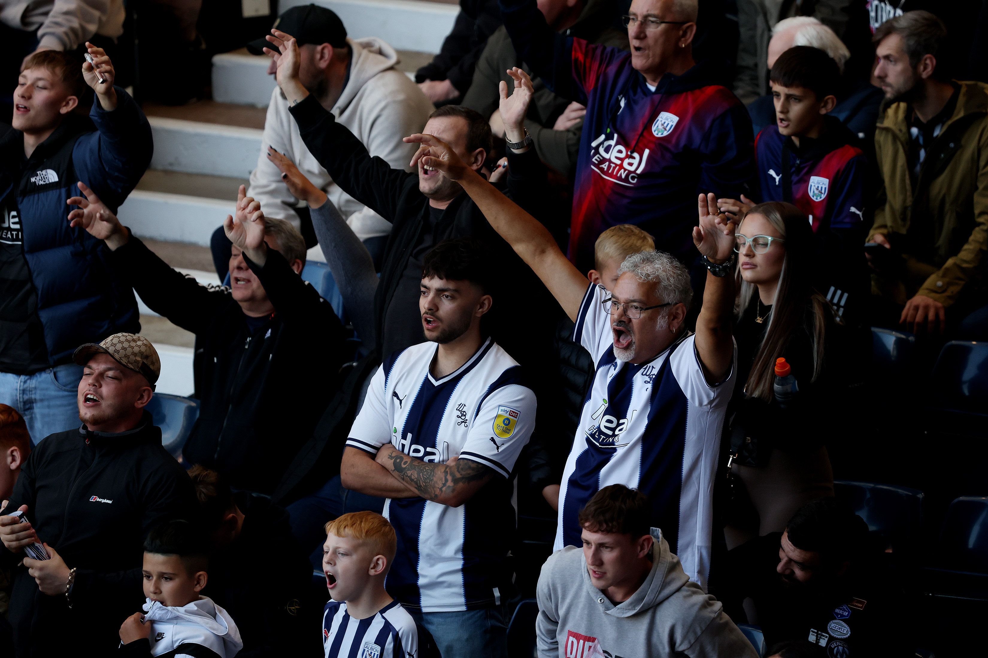Albion fans with their hands in the air at a home game