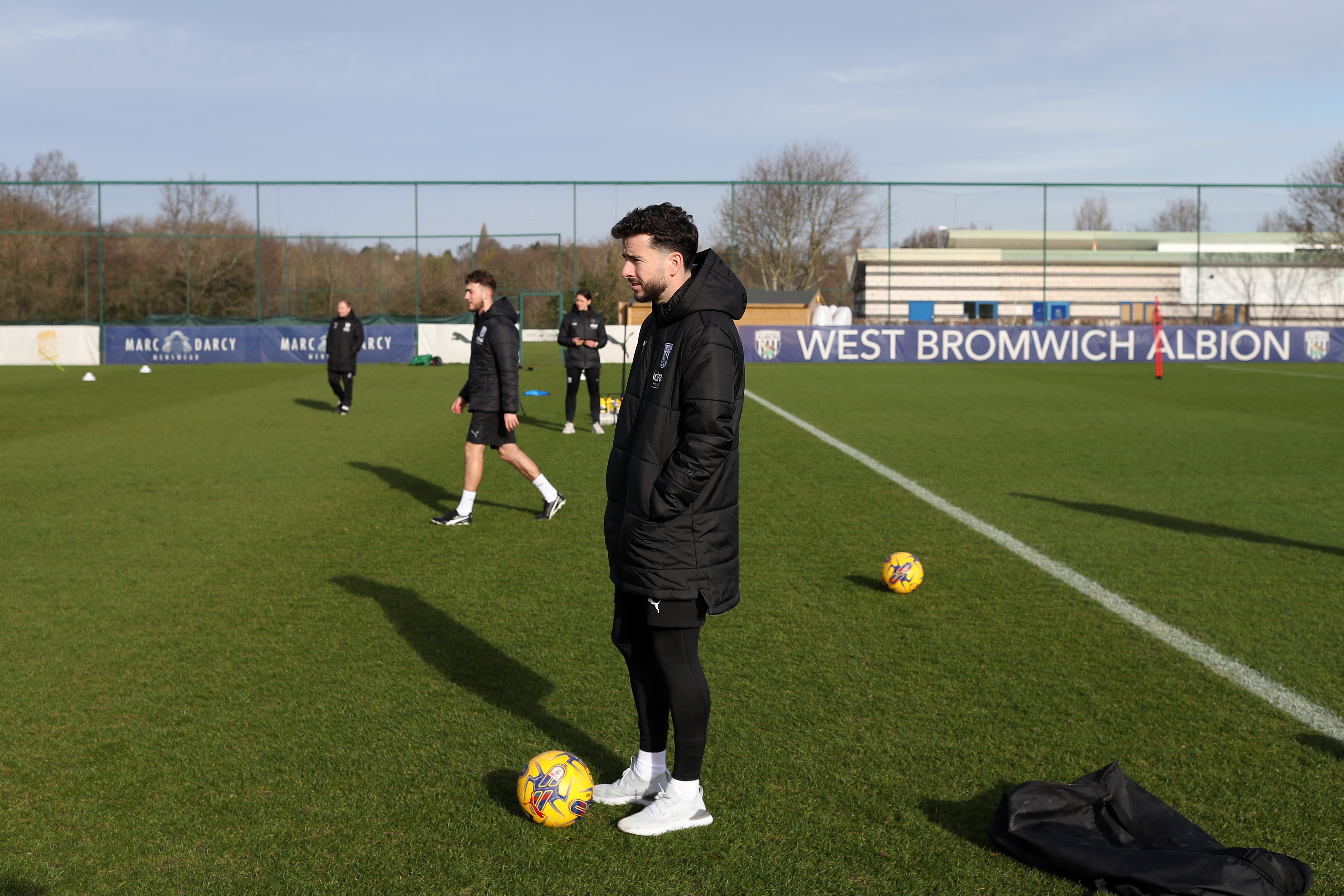 Mikey Johnston watching a training session wearing a big Albion coat