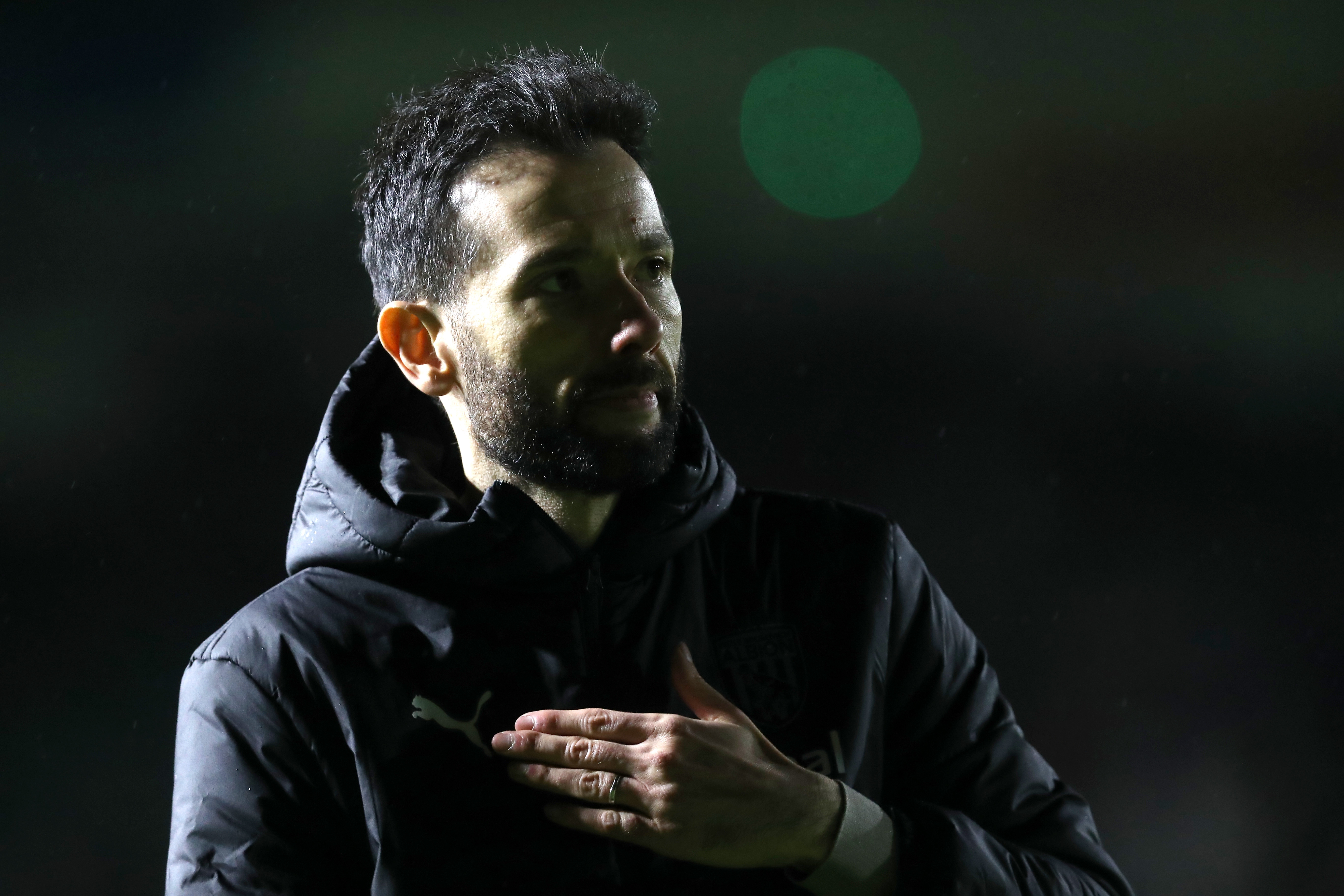 Carlos Corberan touches his heart as he looks at Albion fans in the away end at Plymouth
