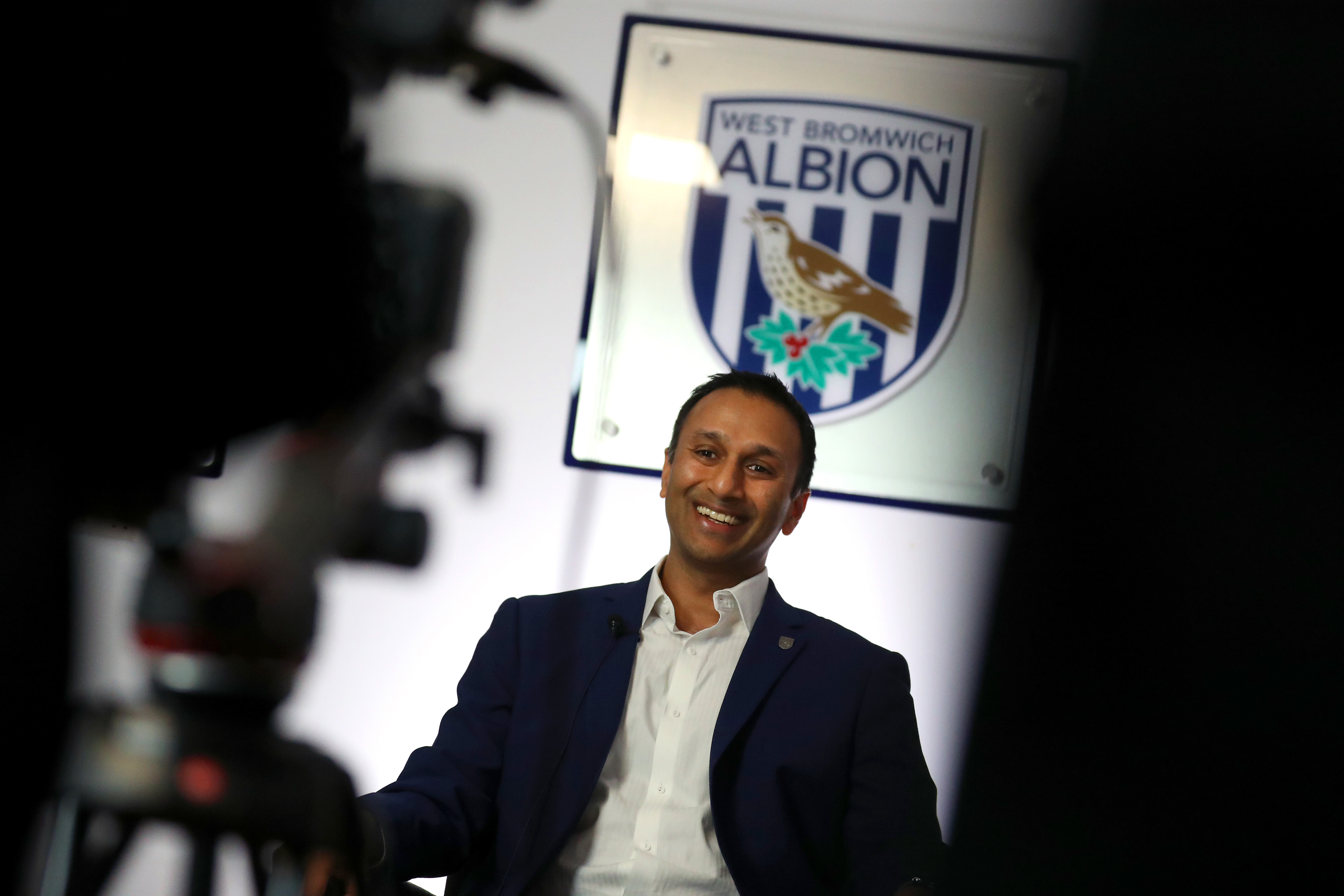 Shilen Patel is interviewed in front of a big Albion badge 