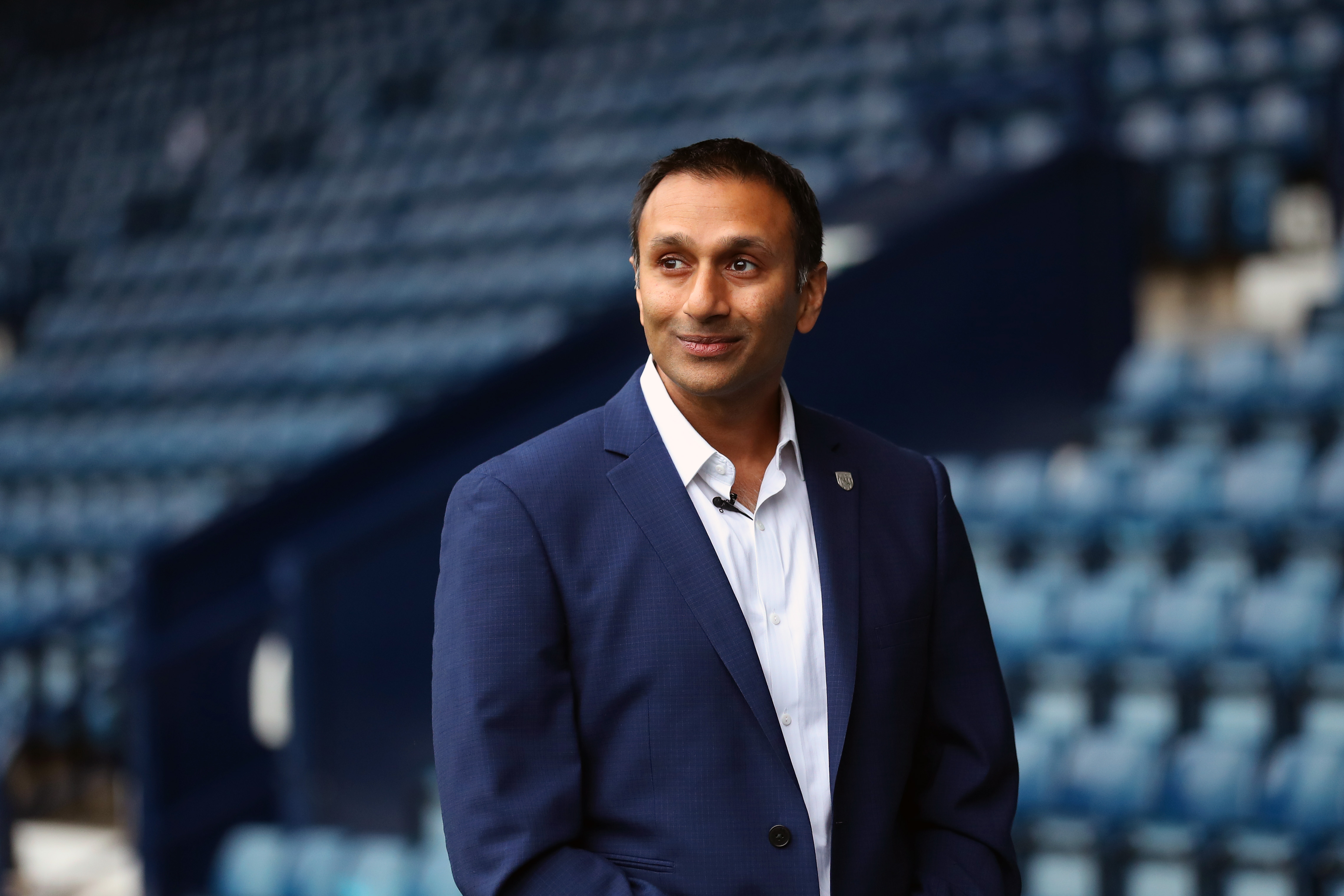 Shilen Patel looking out on to the pitch while walking along the blue track in front of the West Stand at The Hawthorns