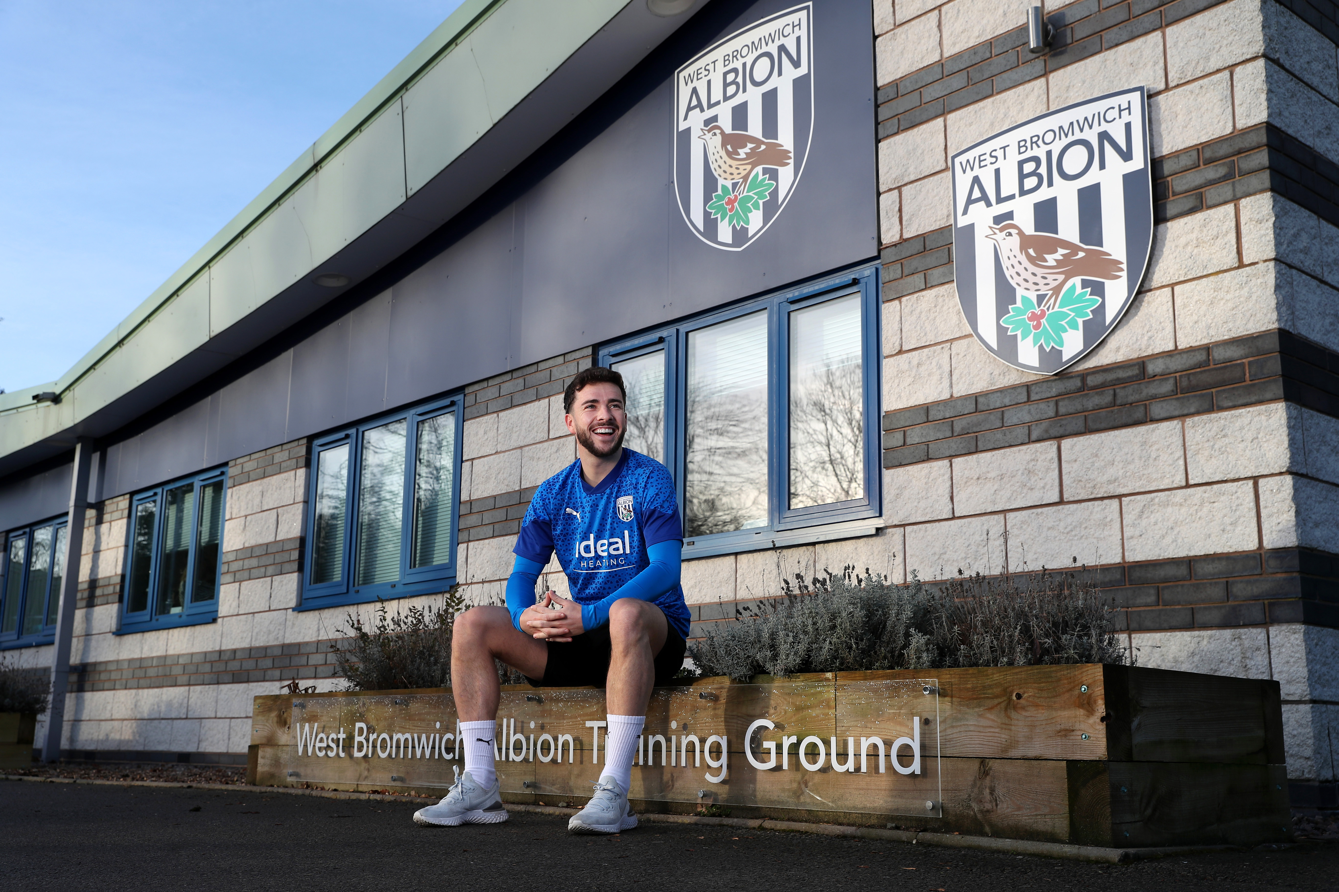 Mikey Johnston smiling sat outside Albion's training ground