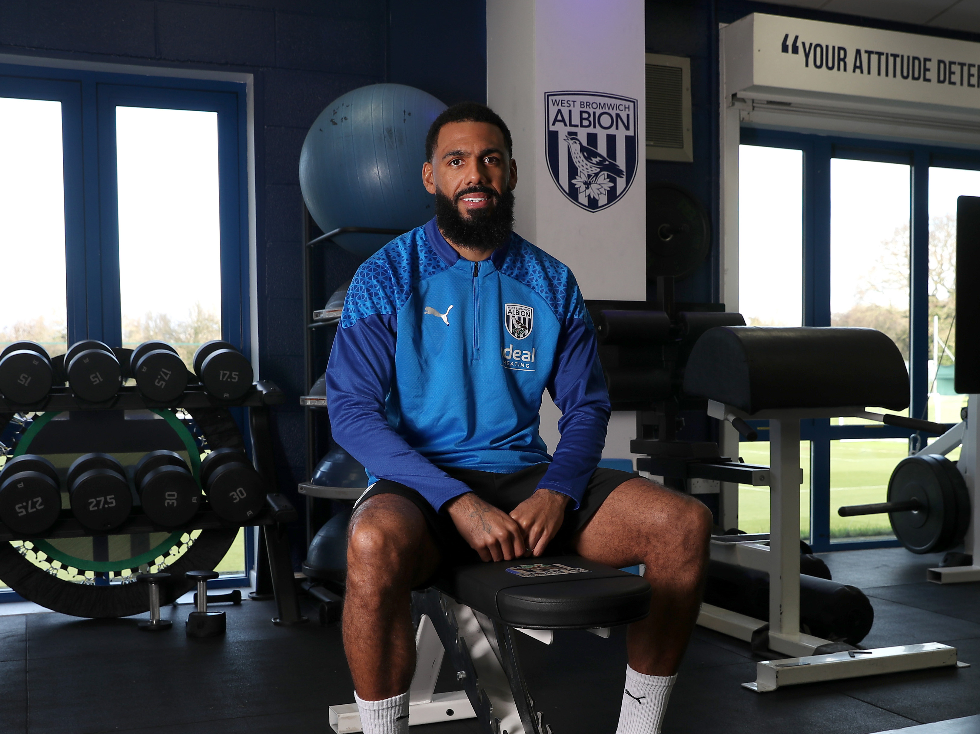 Yann M'Vila sat looking at the camera smiling in the gym