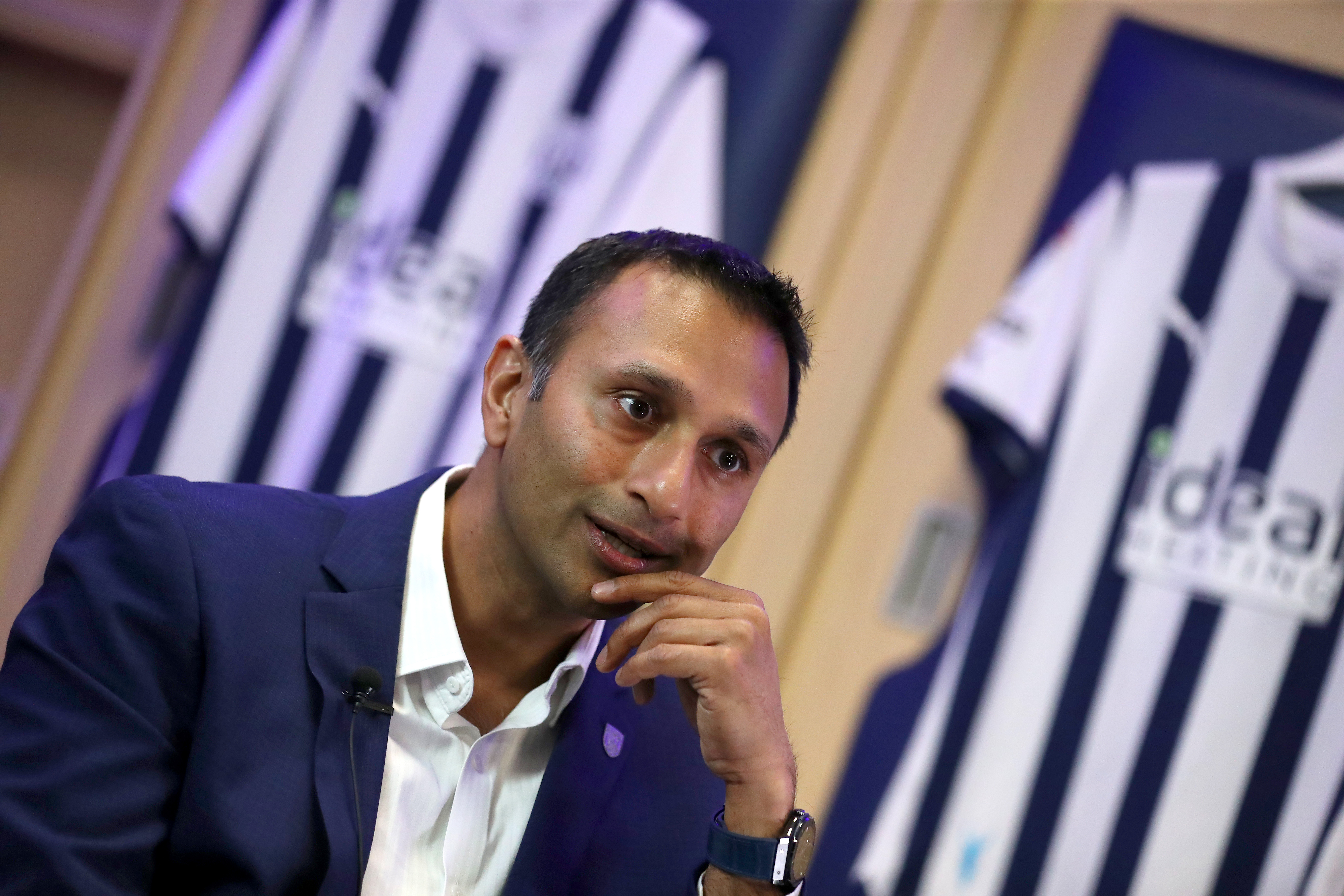 Shilen Patel is interviewed by WBA TV in the home dressing room at The Hawthorns with an Albion shirt behind him 