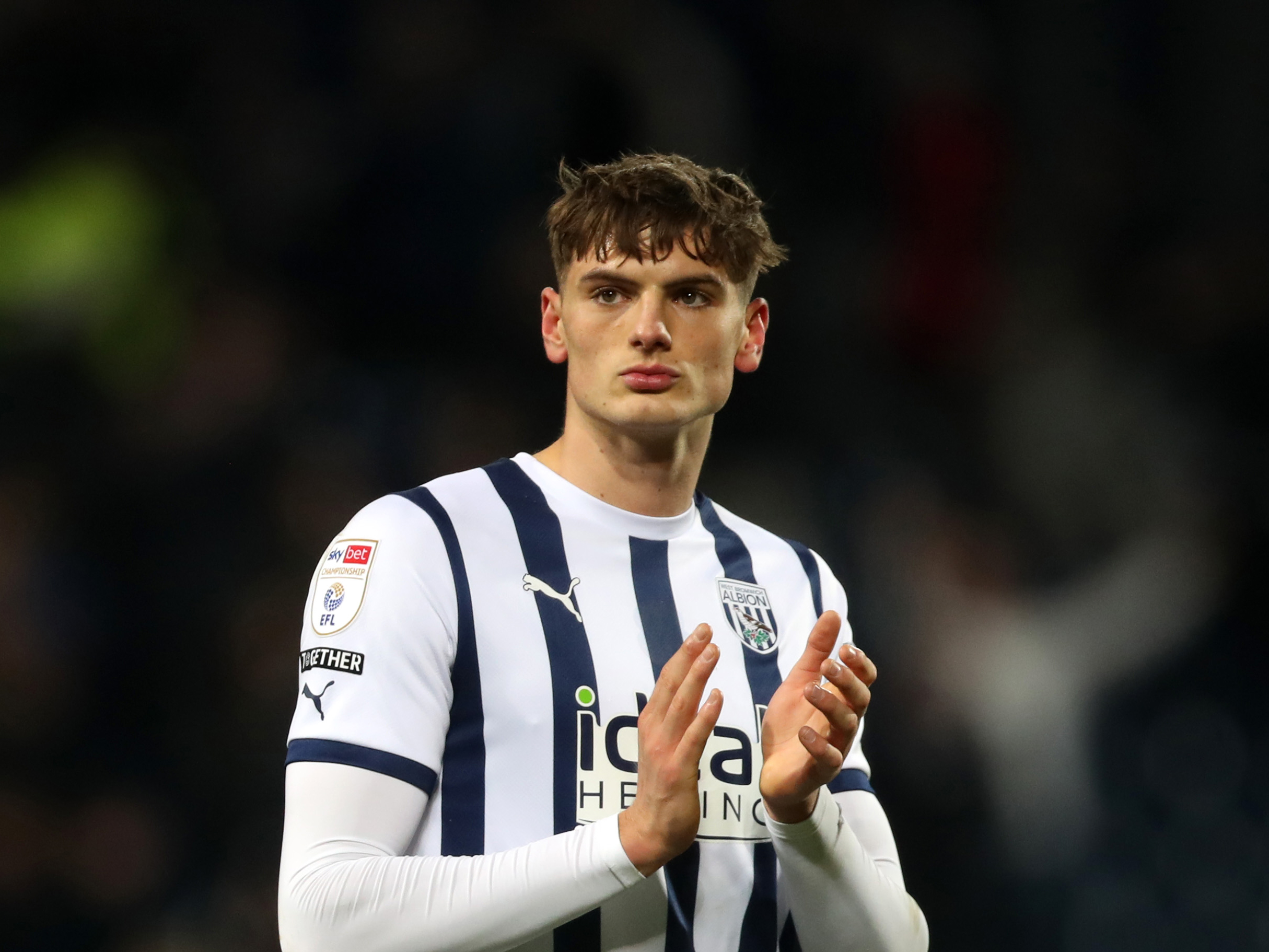 Caleb Taylor applauding Albion supporters while wearing a home shirt