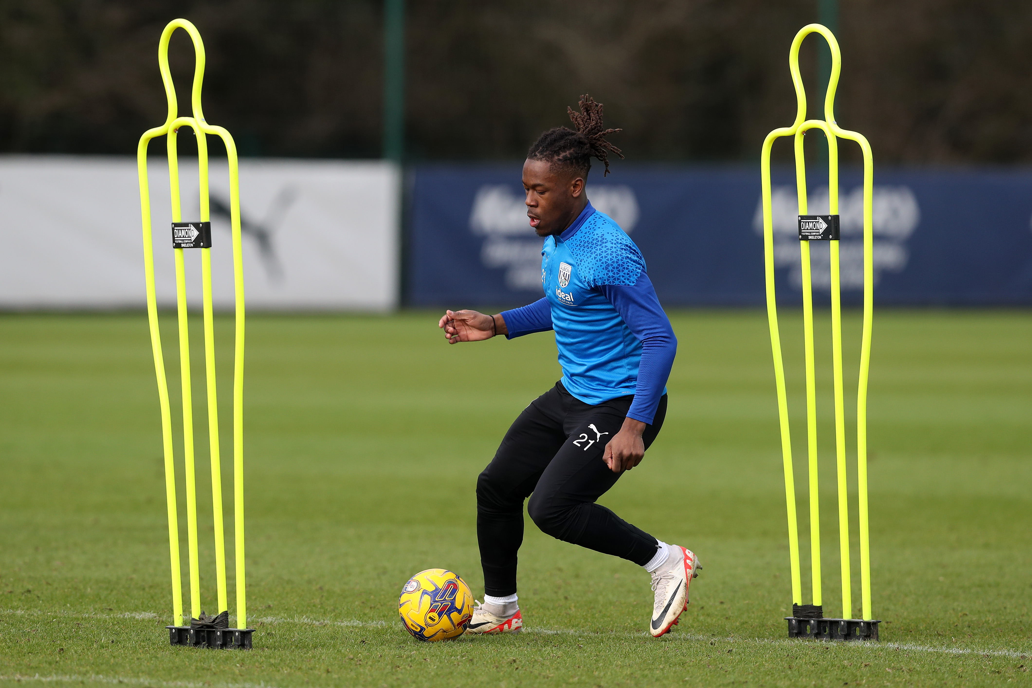 Brandon Thomas-Asante on the ball in training with a mannequin either side of him