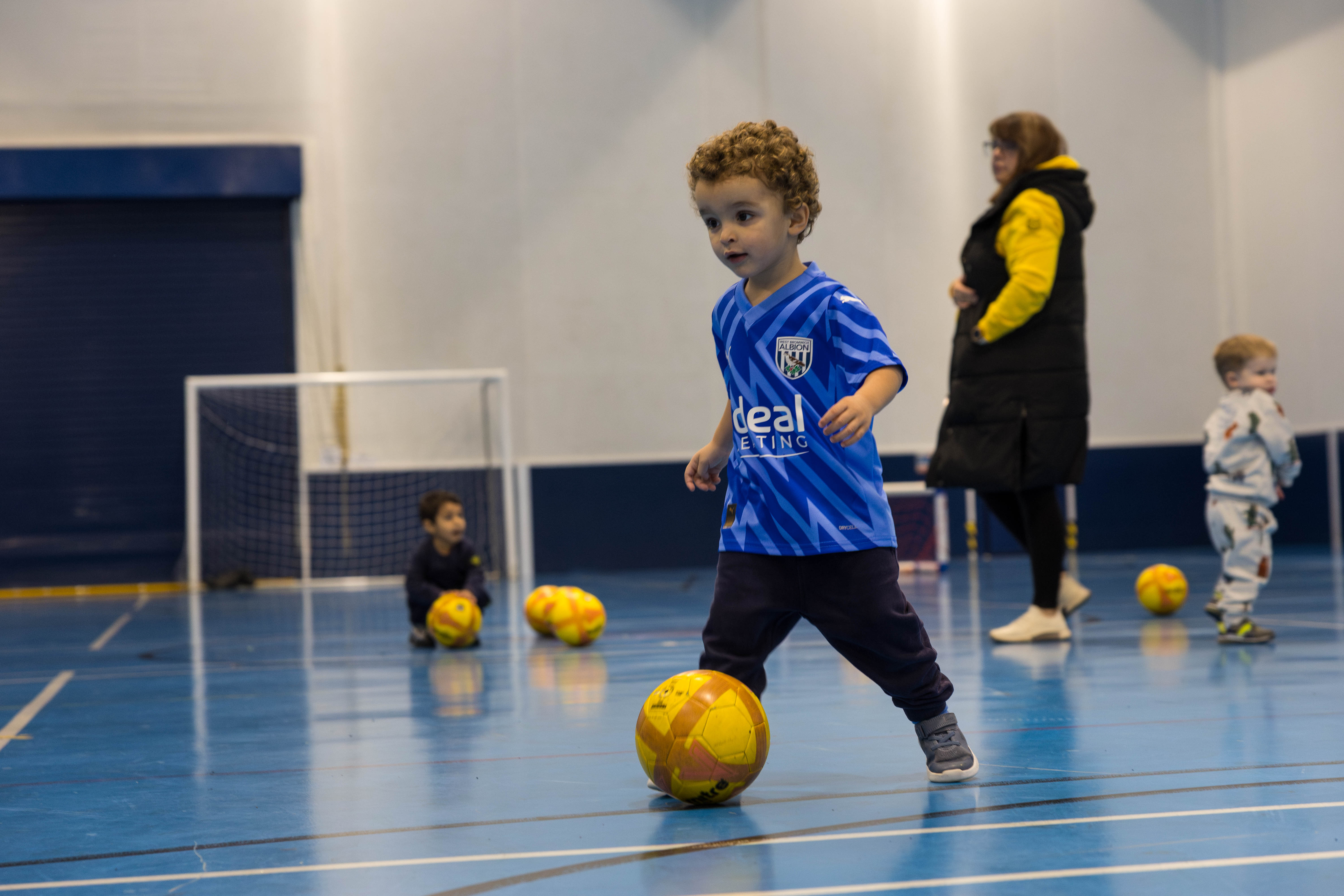 Mini Baggies participant in blue WBA kit, playing with a football