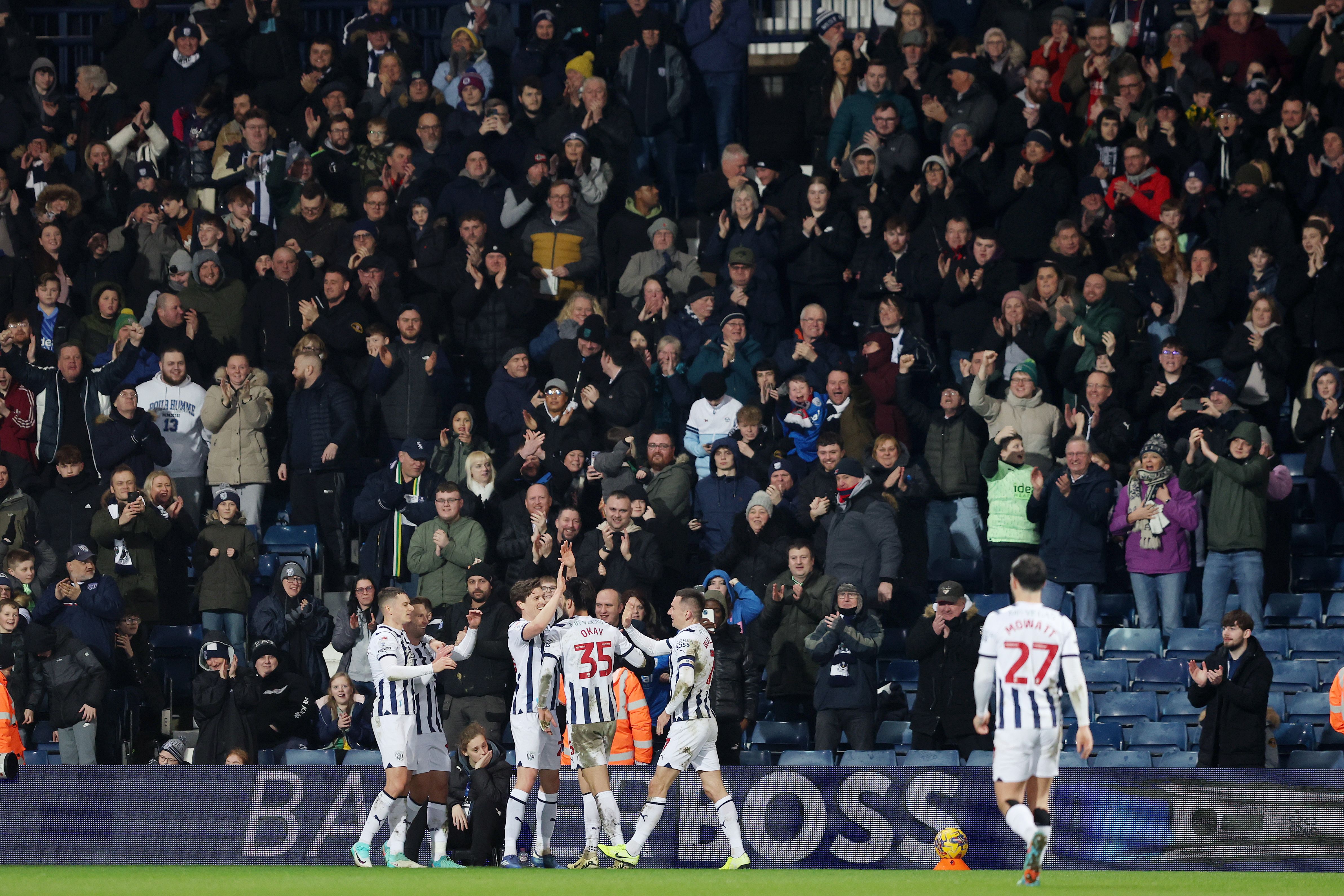 Albion players celebrate scoring against Cardiff with supporters in the stands behind them