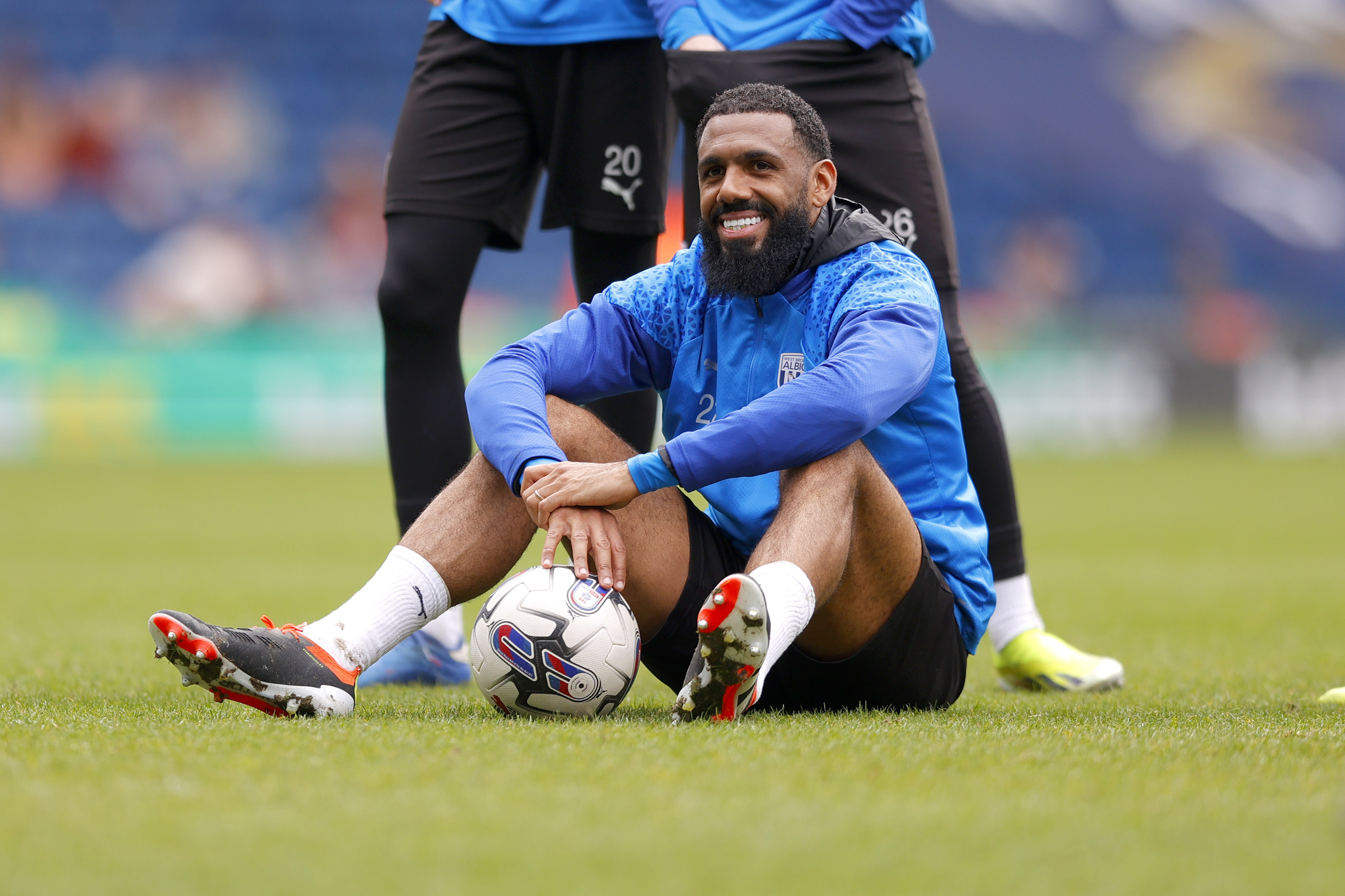 Yann M'Vila smiling while sat on the pitch at The Hawthorns