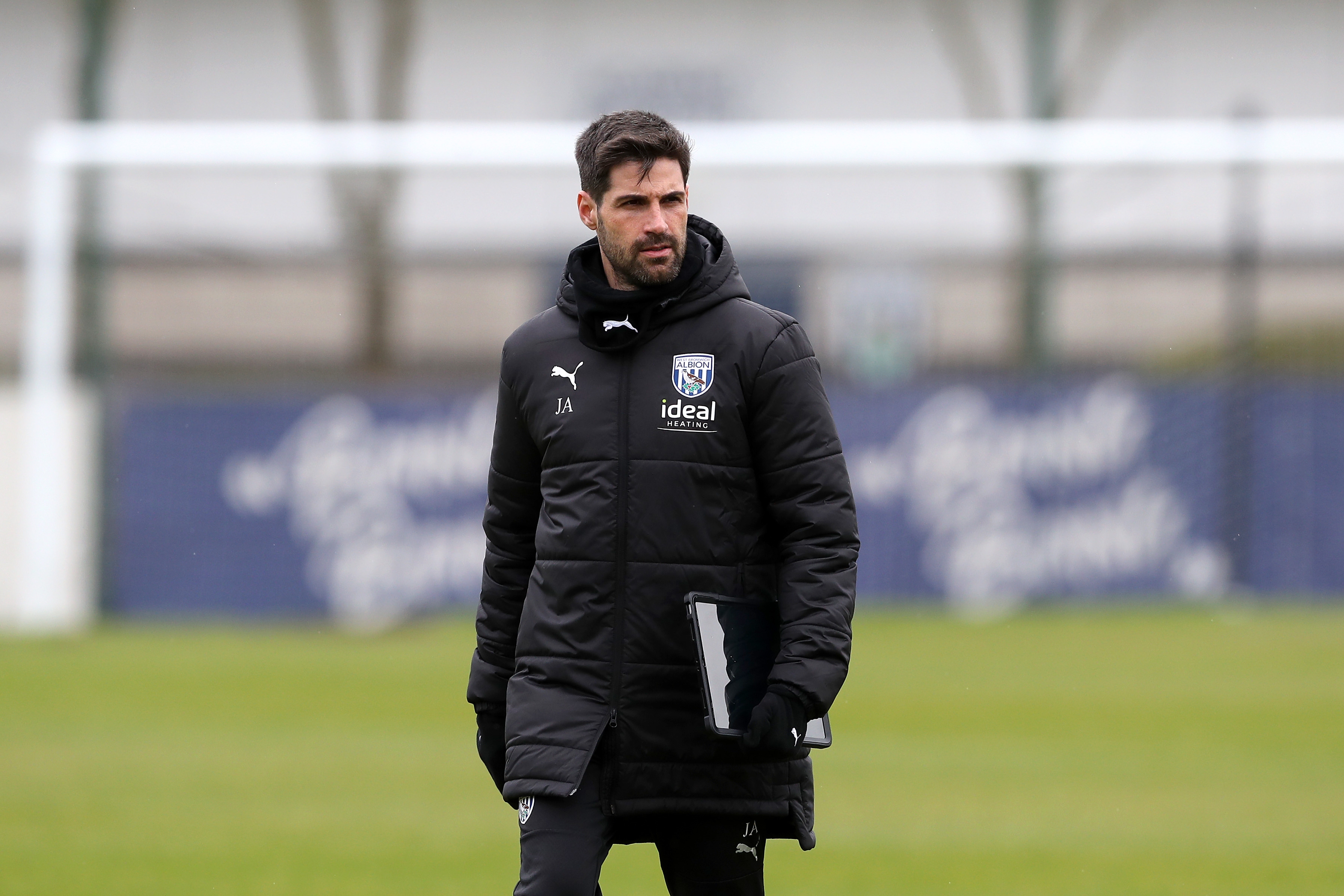 Jorge Alarcon wearing a black coat holding a notepad out on the training pitch