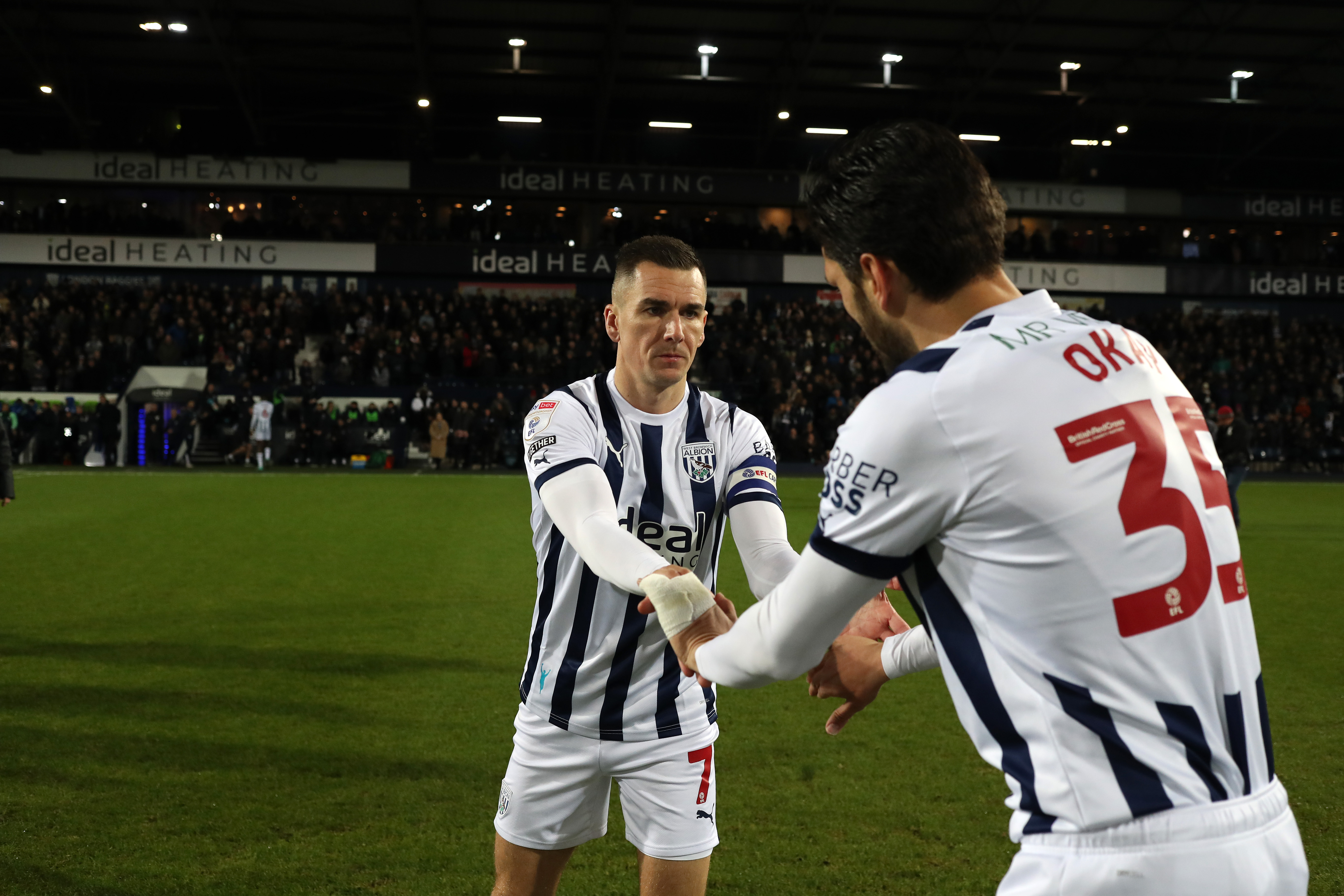 Jed Wallace and Okay Yokuslu slap hands before a game at The Hawthorns both wearing home kits
