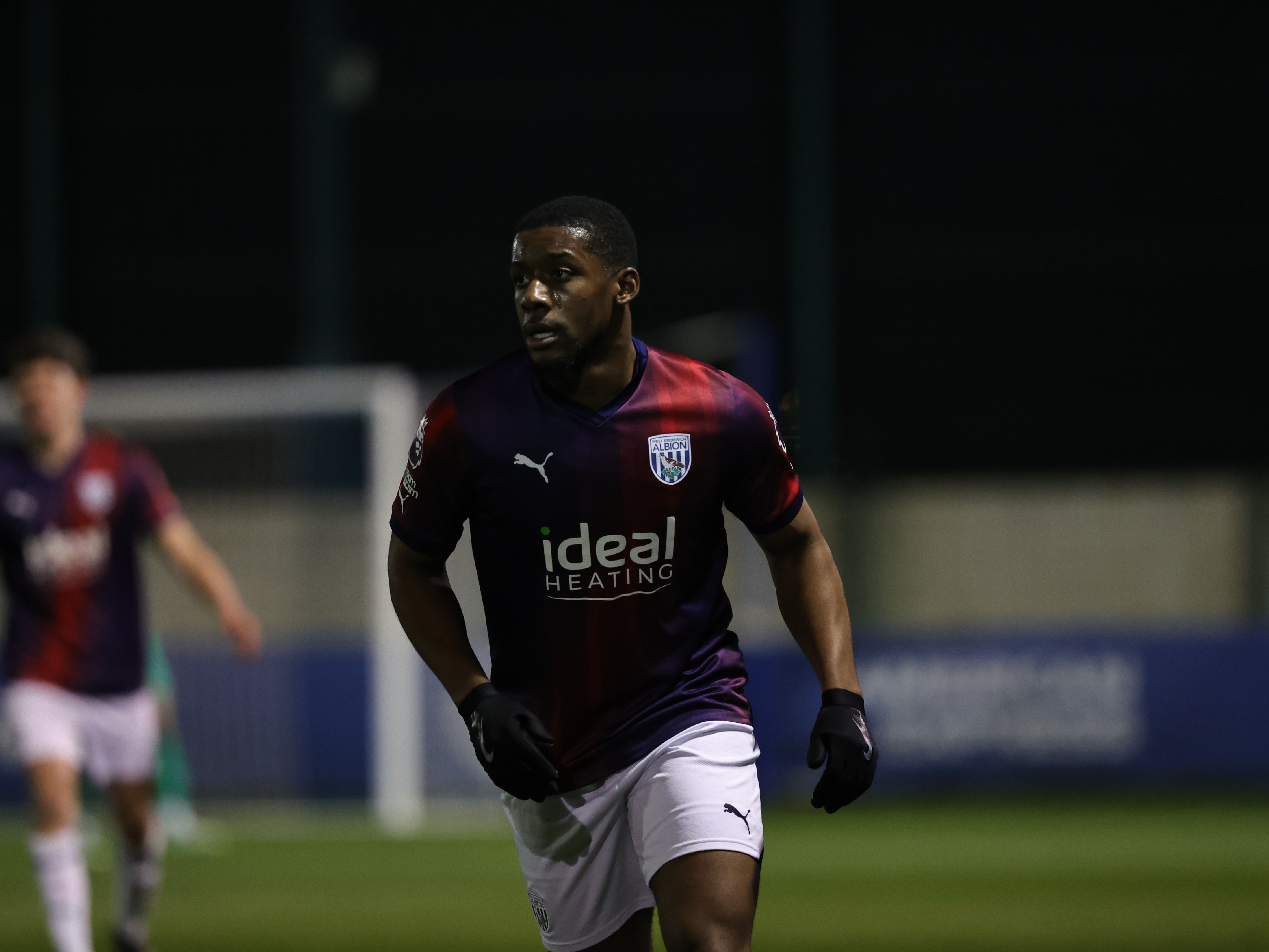 A photo of Jovan Malcolm in the 23/24 red and blue kit in action in the PL2 v Brighton