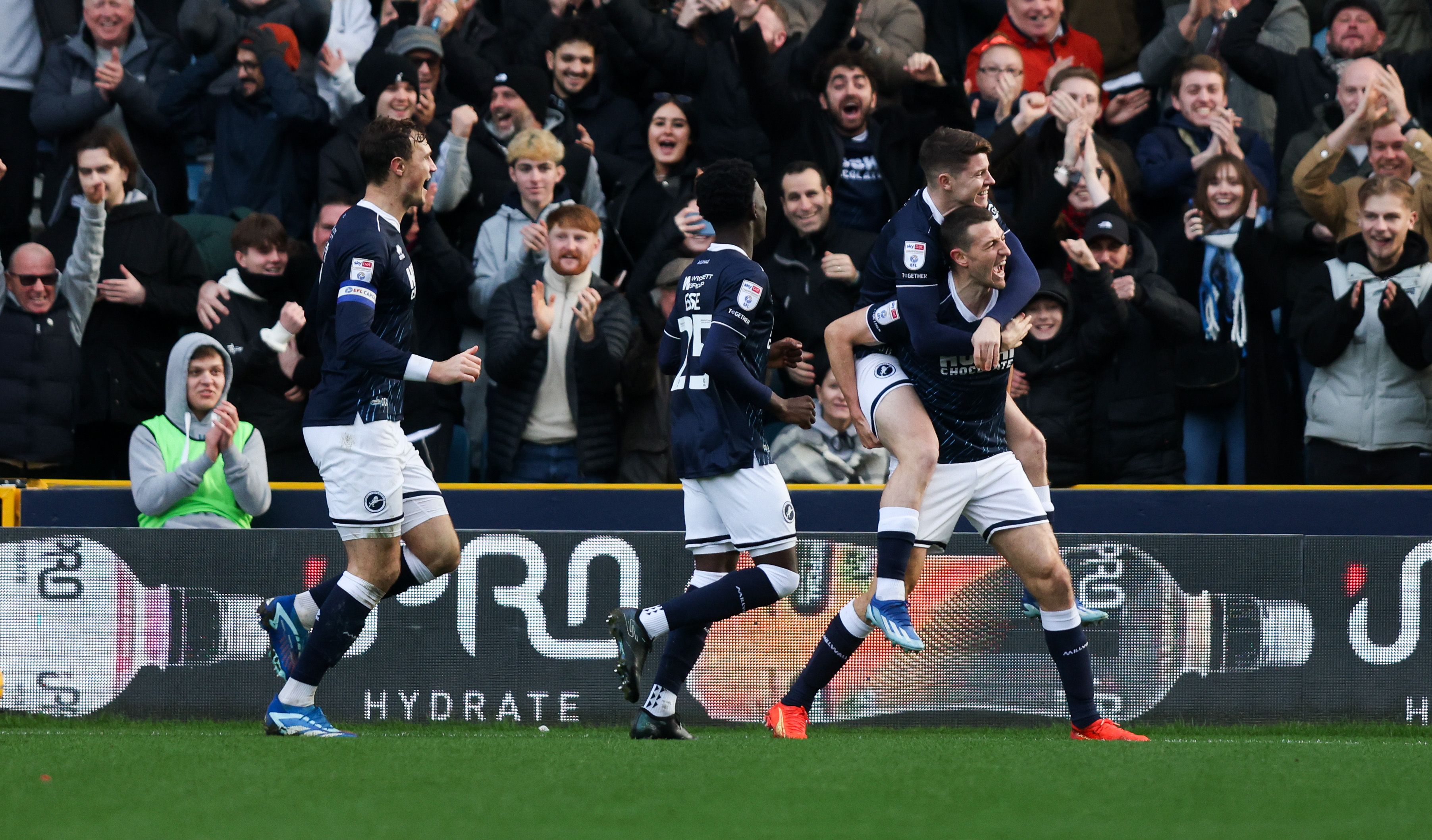 Millwall players celebrate a goal in front of their own celebrating fans
