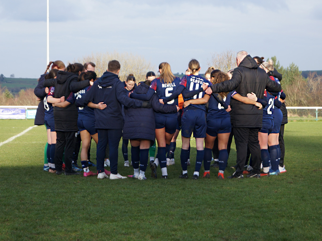 An image of the Albion Women squad in a huddle after their win at Huddersfield