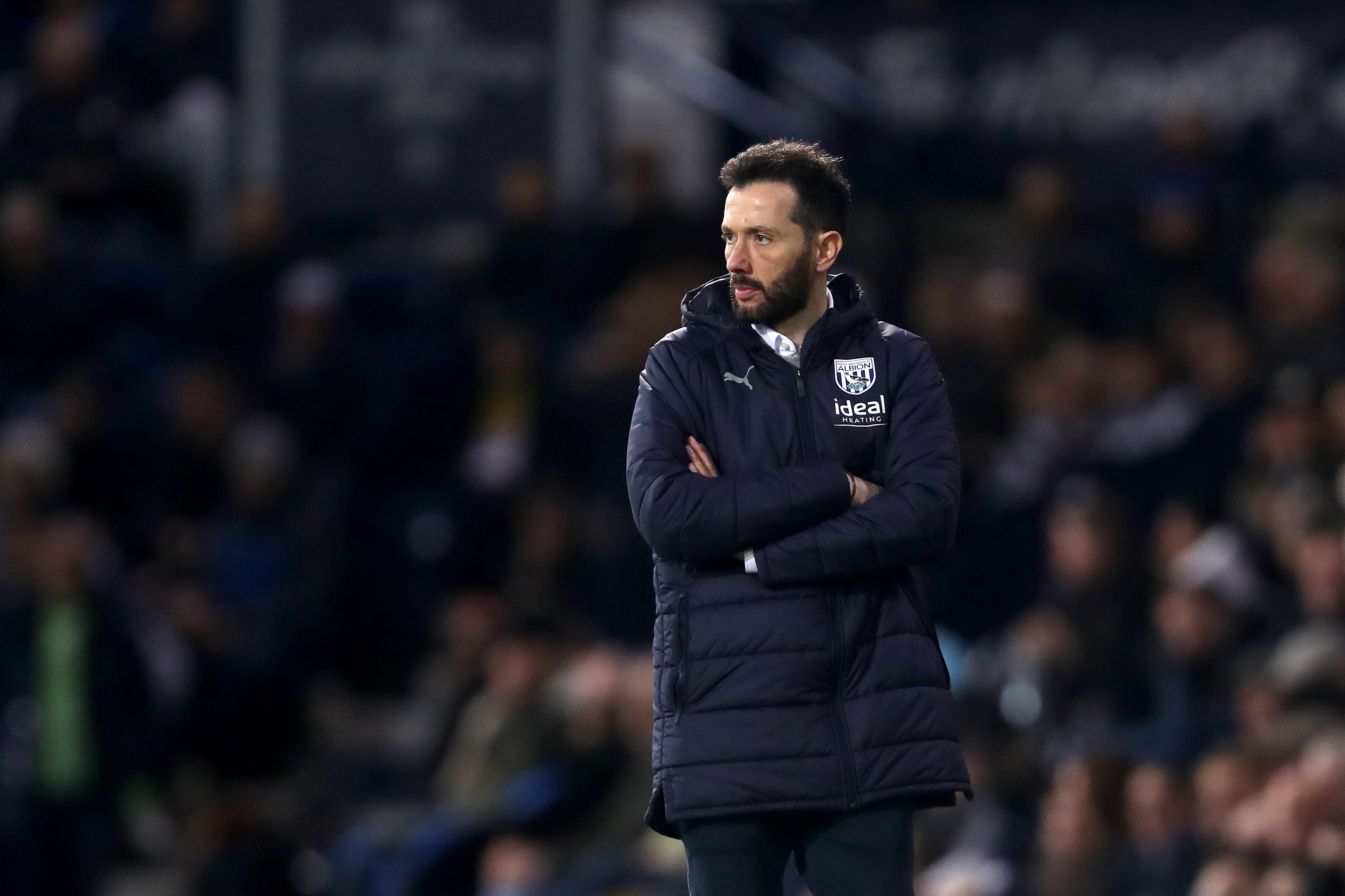 Carlos Corberán folding his arms while wearing an Albion coat on the side of the pitch at The Hawthorns during the game against Rotherham United