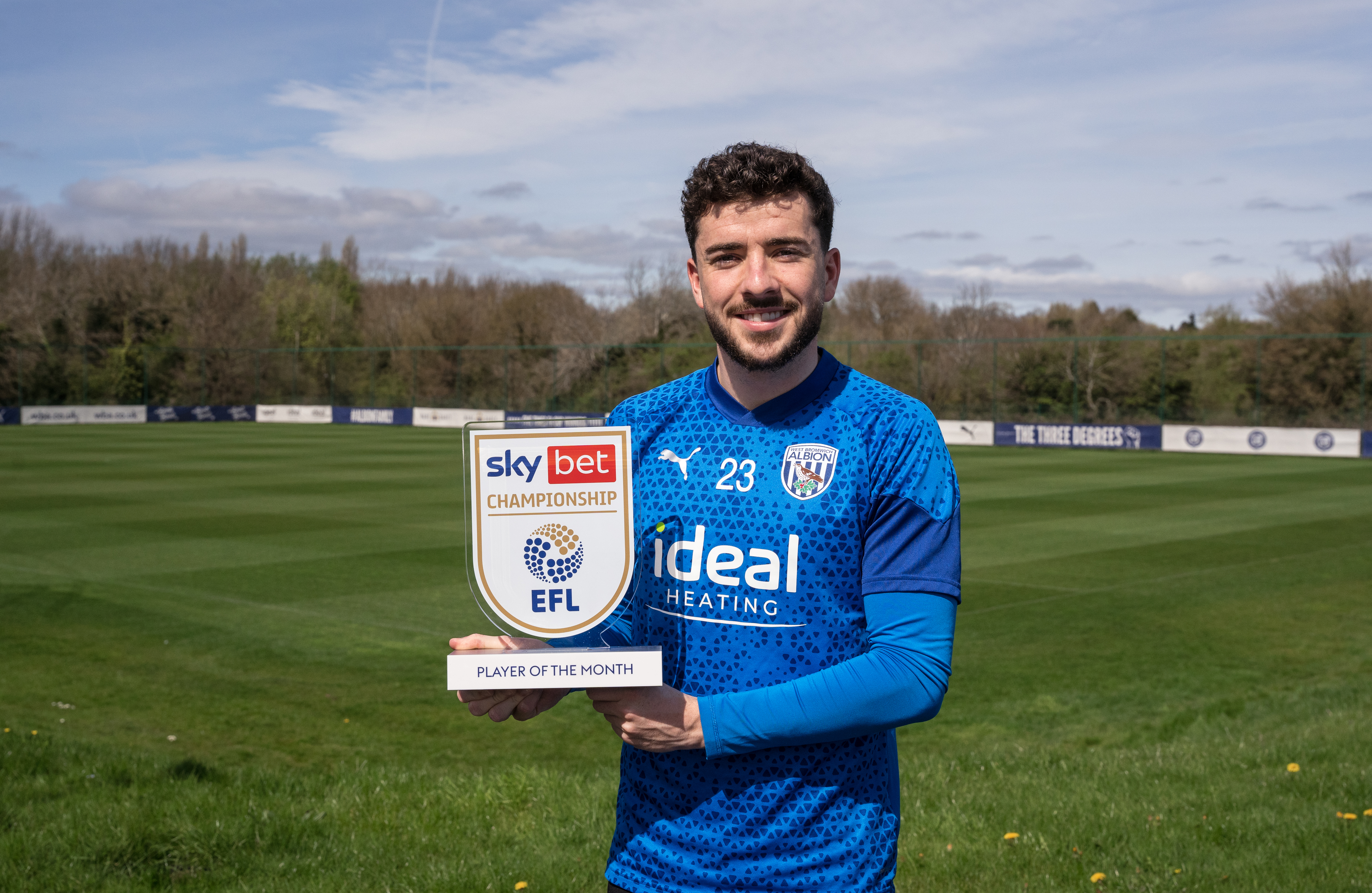 Mikey Johnston holding his Player of the Month trophy while wearing Albion training kit