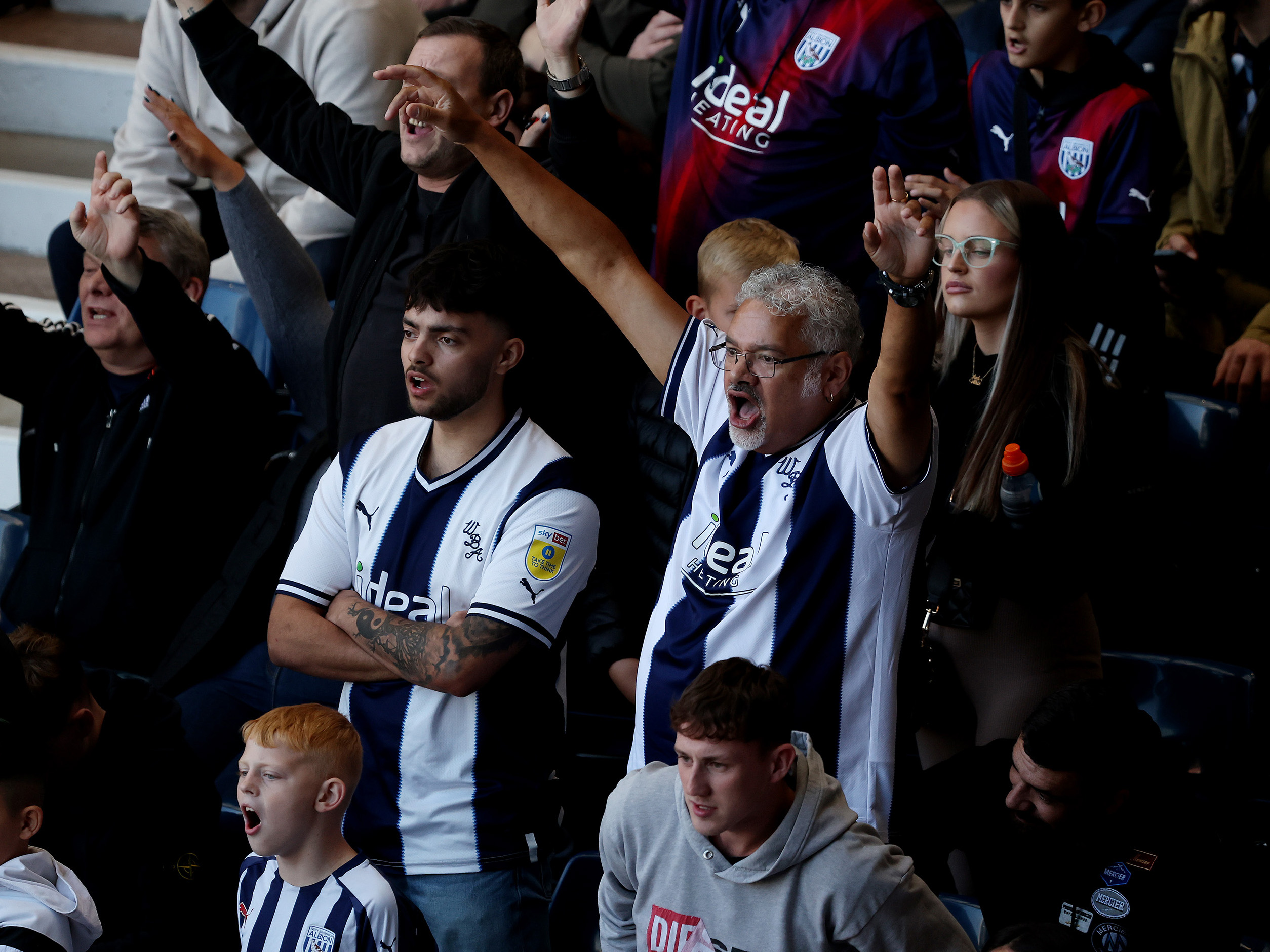 Albion fans cheering at The Hawthorns wearing home shirts