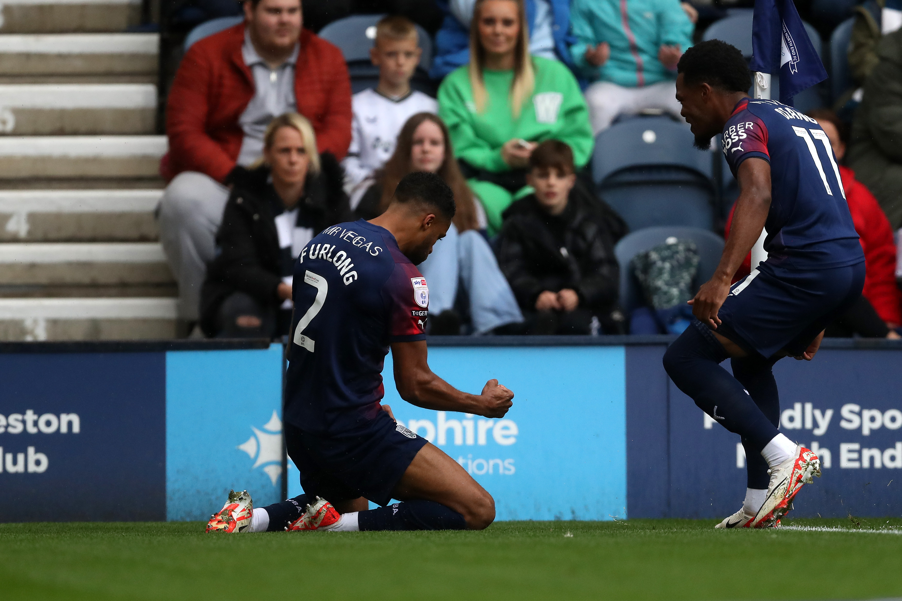 Darnell Furlong celebrates scoring at Preston North End with Grady Diangana while wearing the navy blue and red away kit 