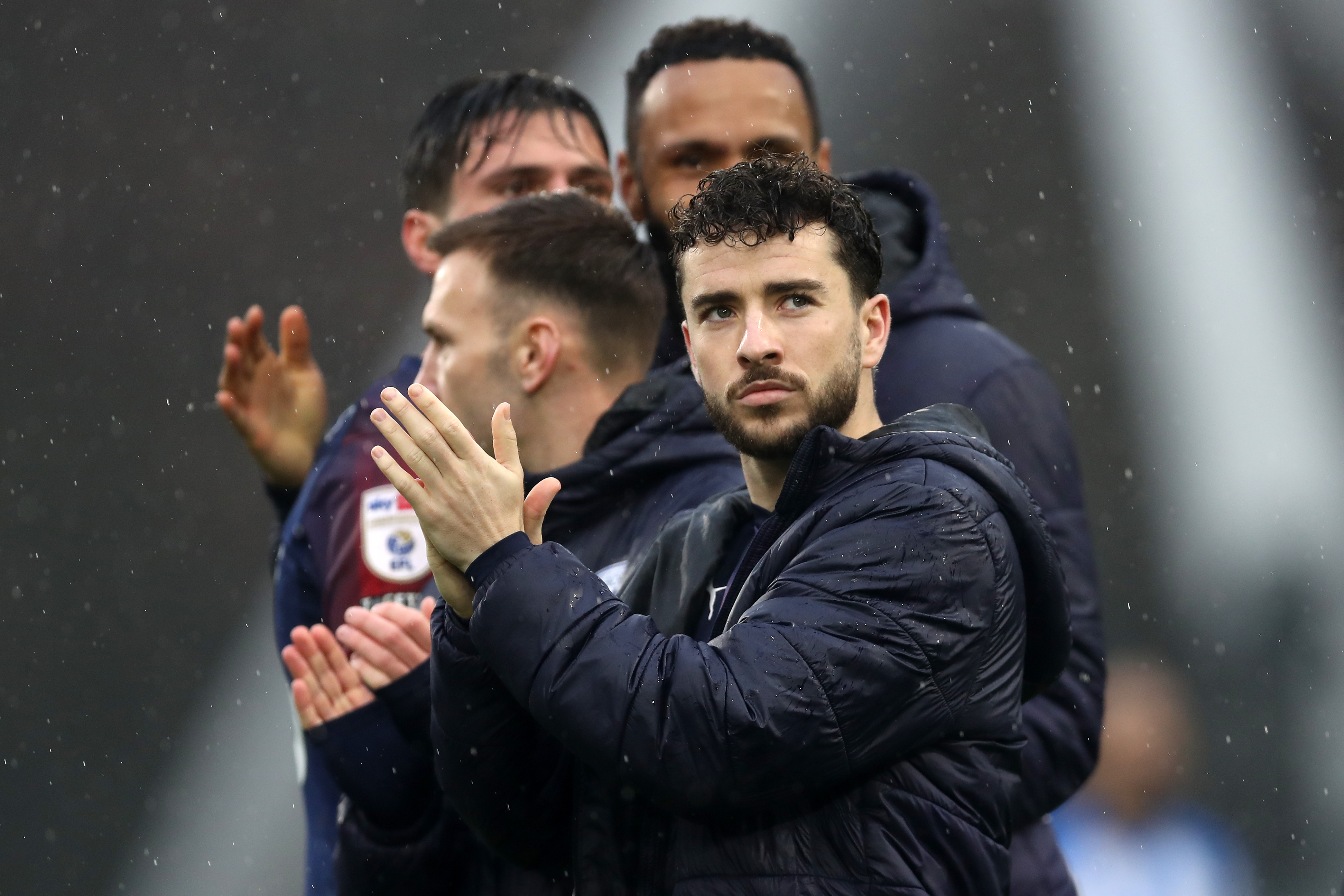 Mikey Johnston applauding Albion fans while wearing a coat in the rain