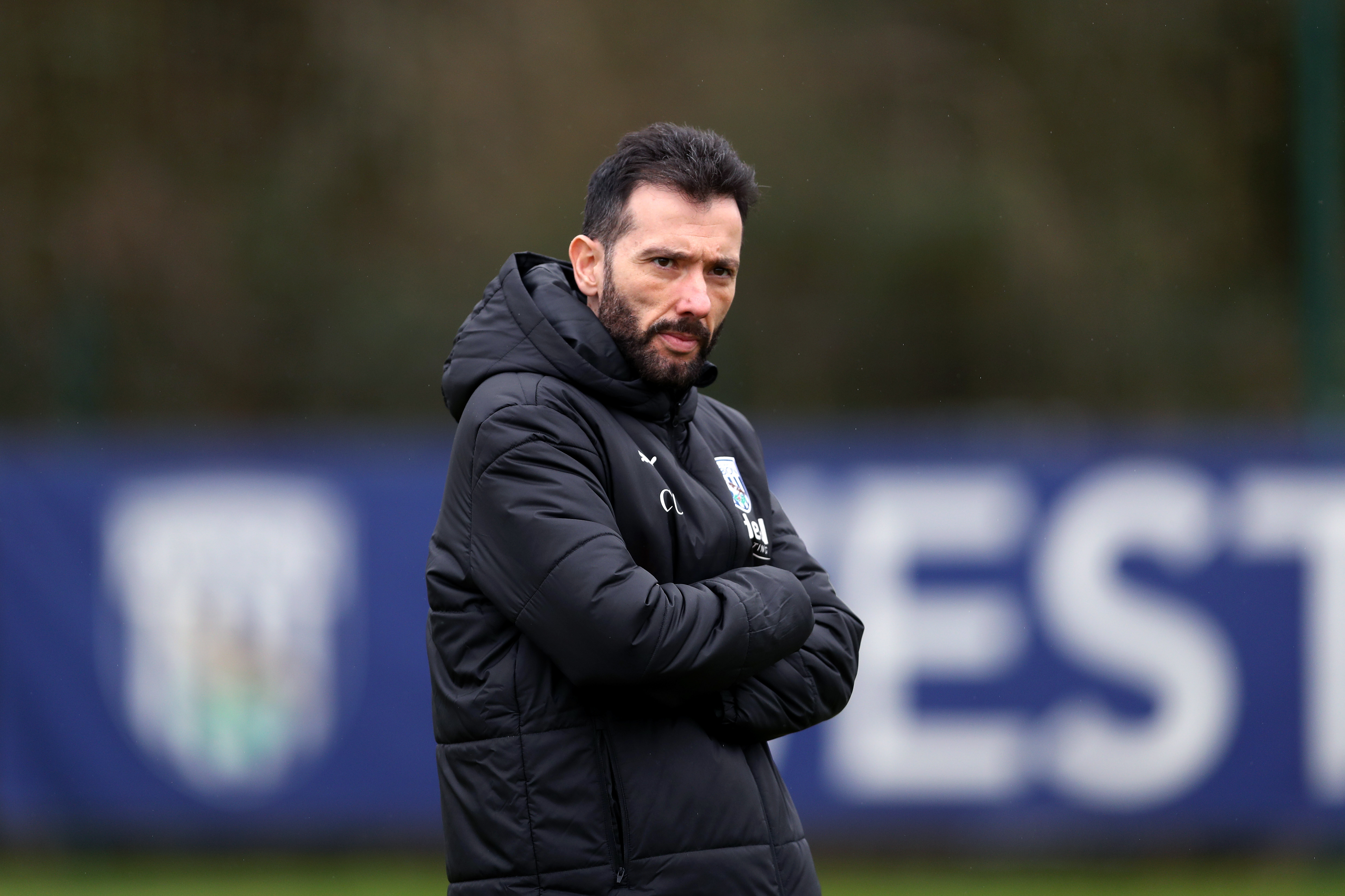 Carlos Corberán looking at the camera while wearing a black Albion coat in the middle of a training session