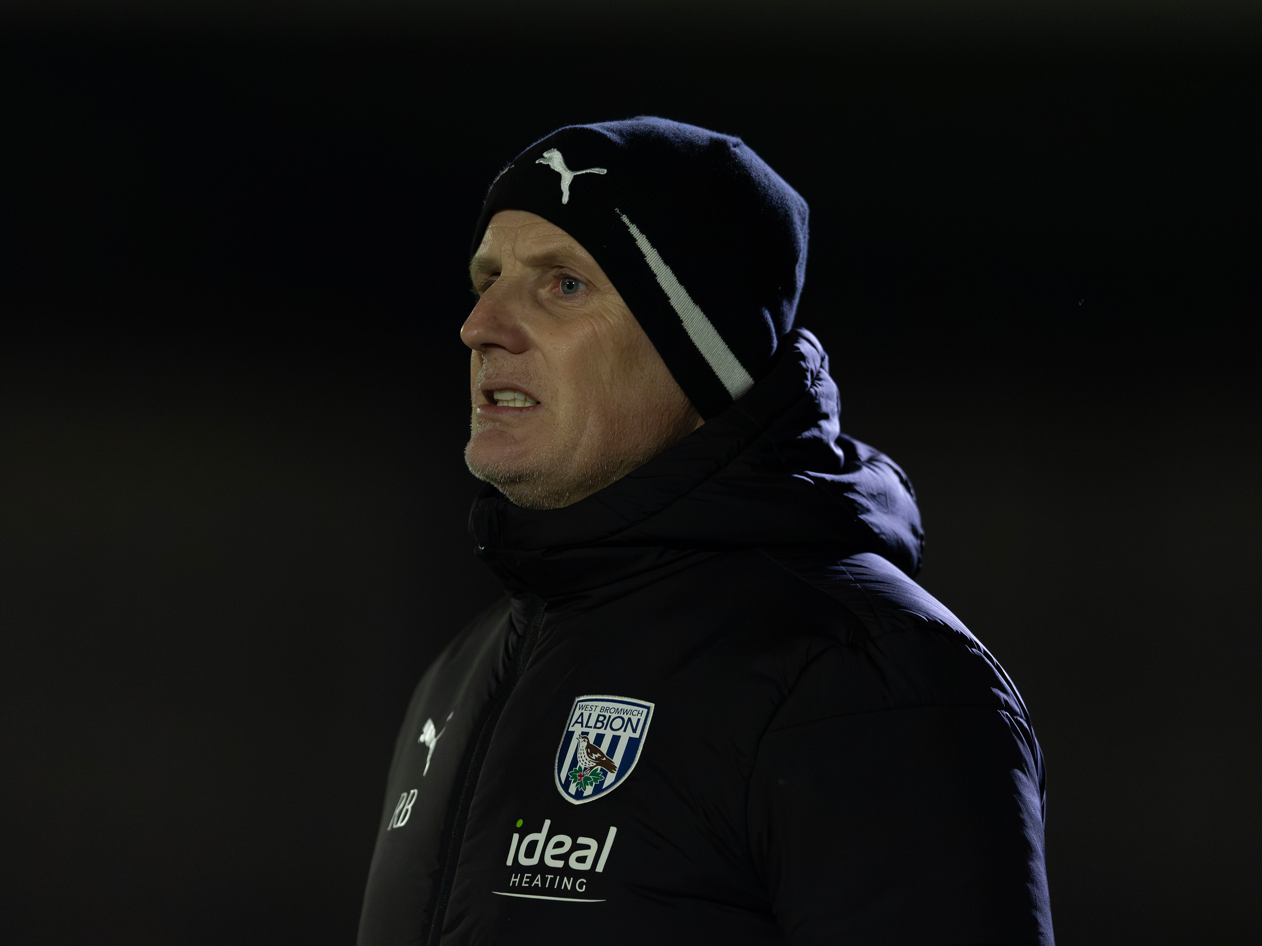 A photo of Albion PL2 boss Richard Beale, pictured in a black coat and hat on the touchline during an U21s game v Arsenal