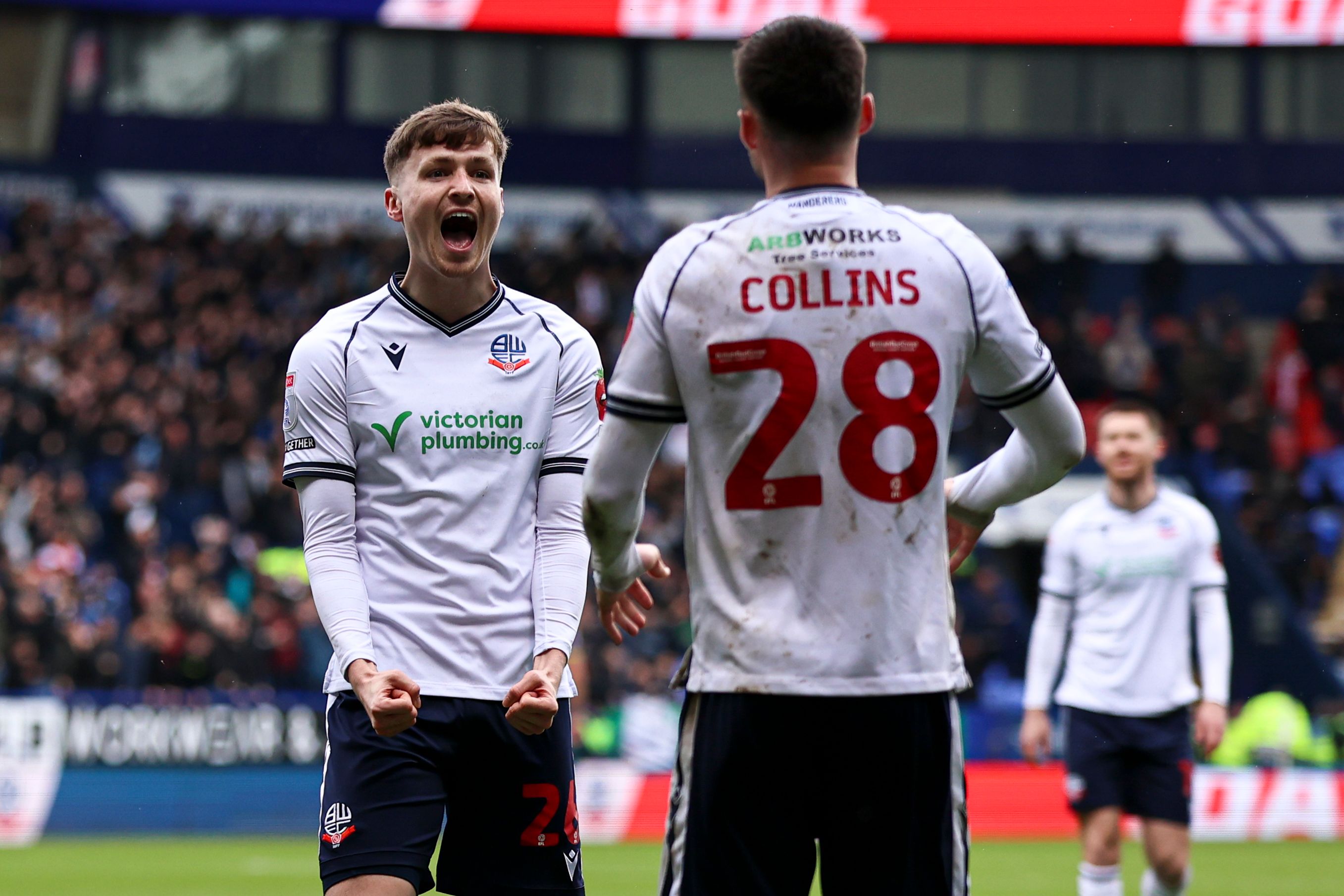 Zac Ashworth celebrates a Bolton goal with a team-mate while wearing Bolton's home shirt