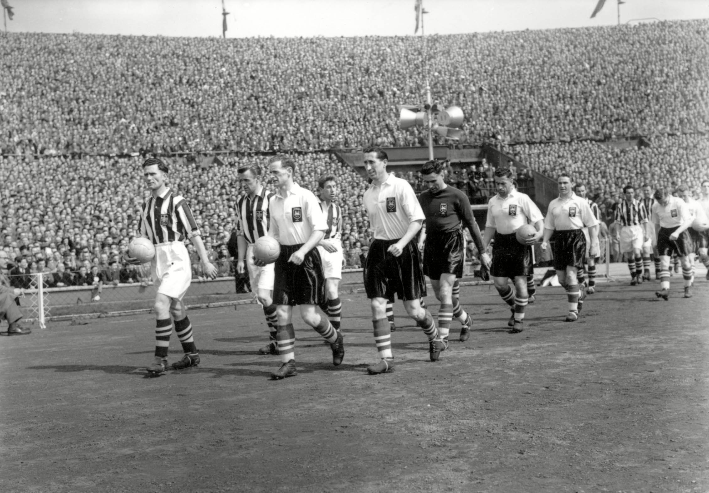 The two teams walk out on to the pitch before the 1954 FA Cup final