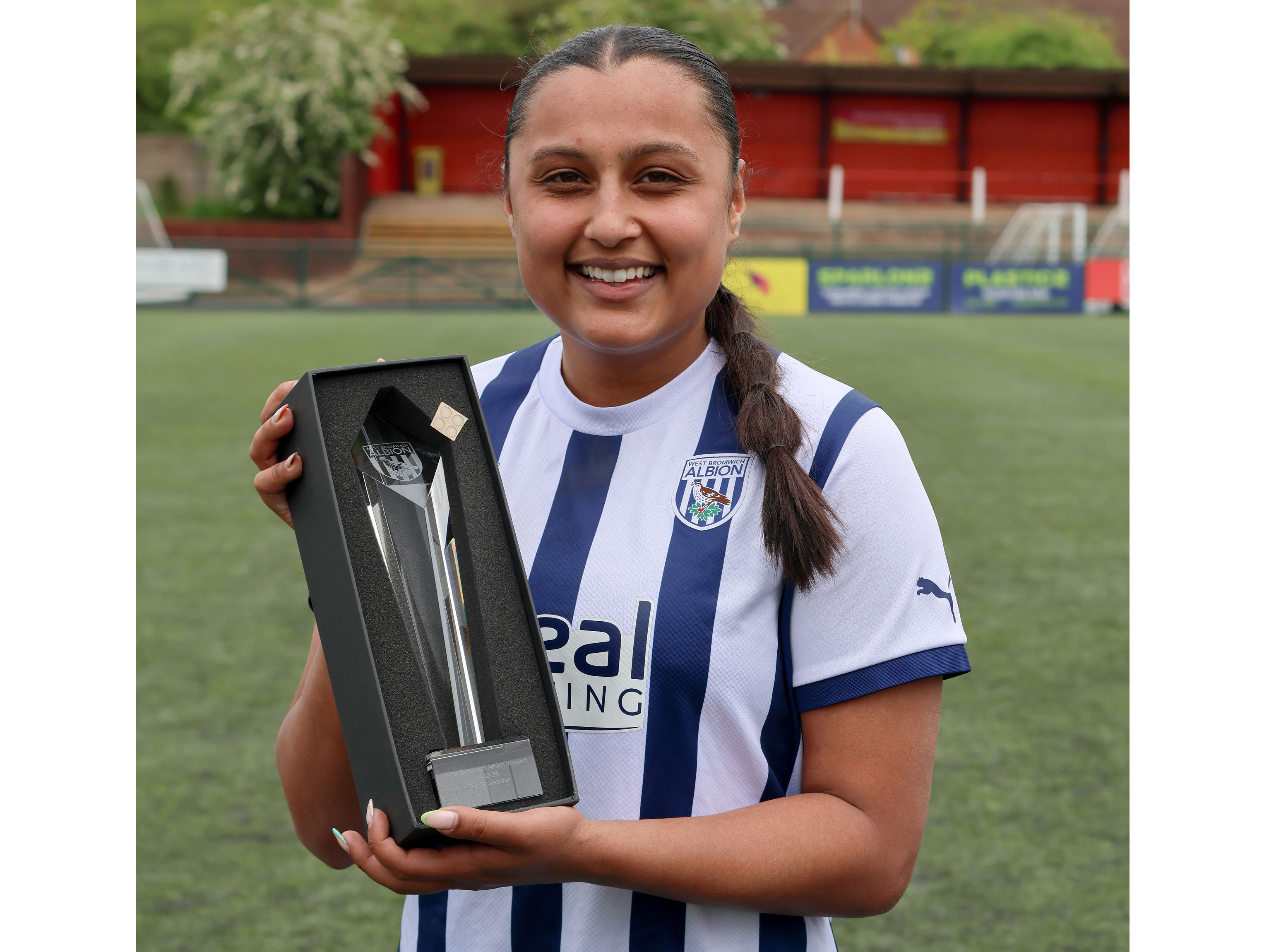 Simran Jhamat posing for a photo with her top scorer award while smiling and wearing the home kit 