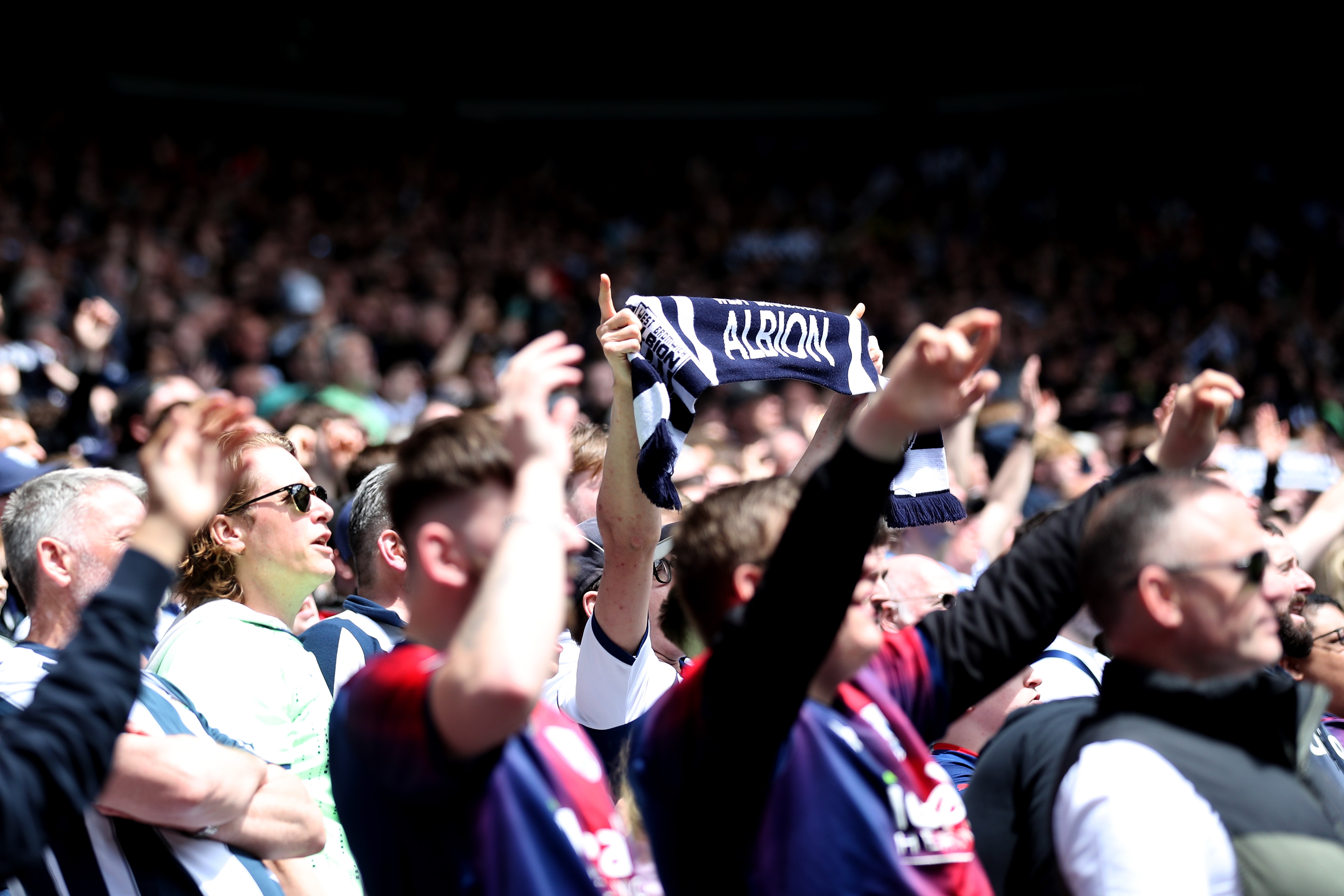 An Albion fan holding up a scarf at the Preston game 