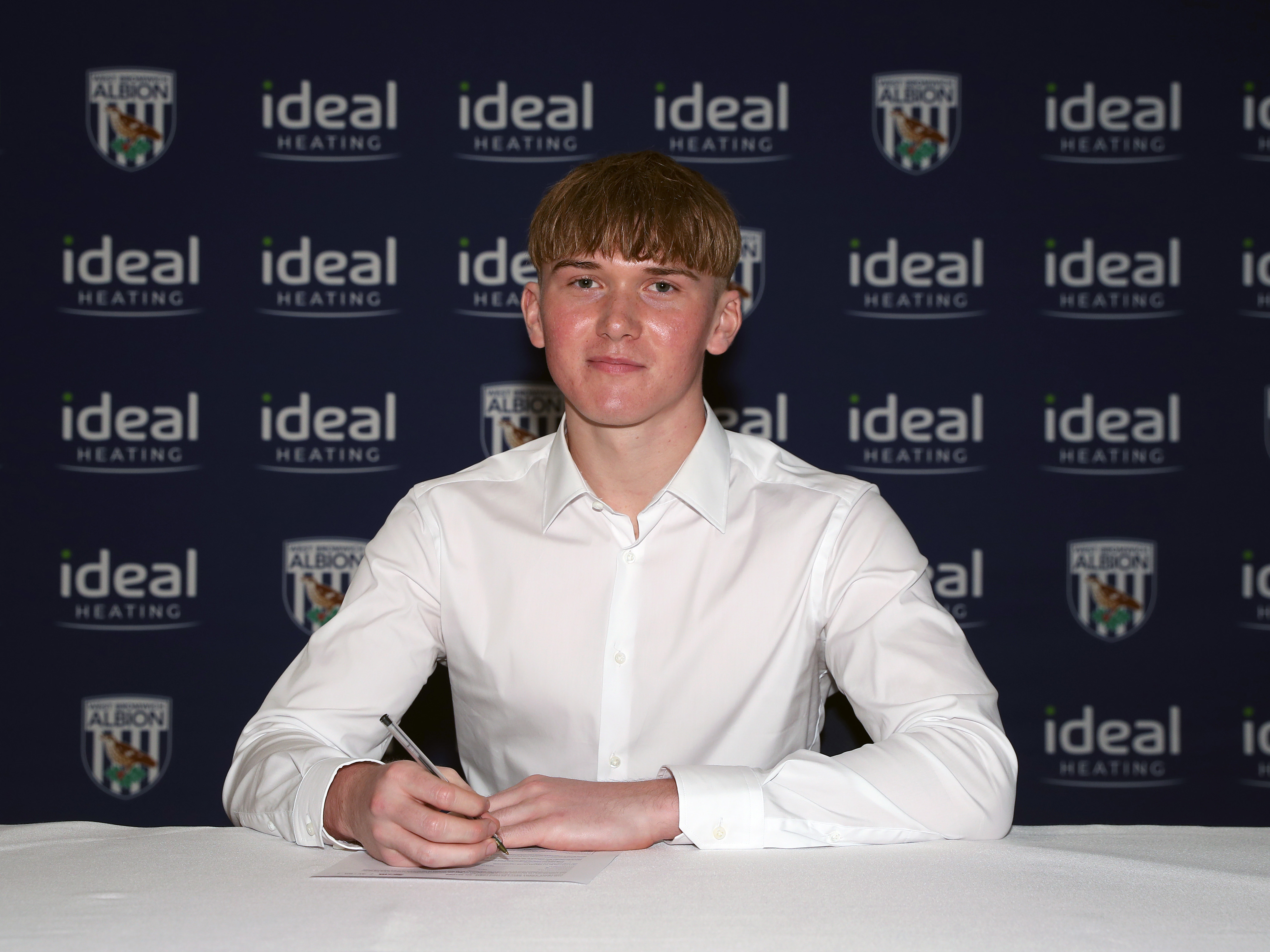 A photo of Liam Wilkes signing his scholarship deal