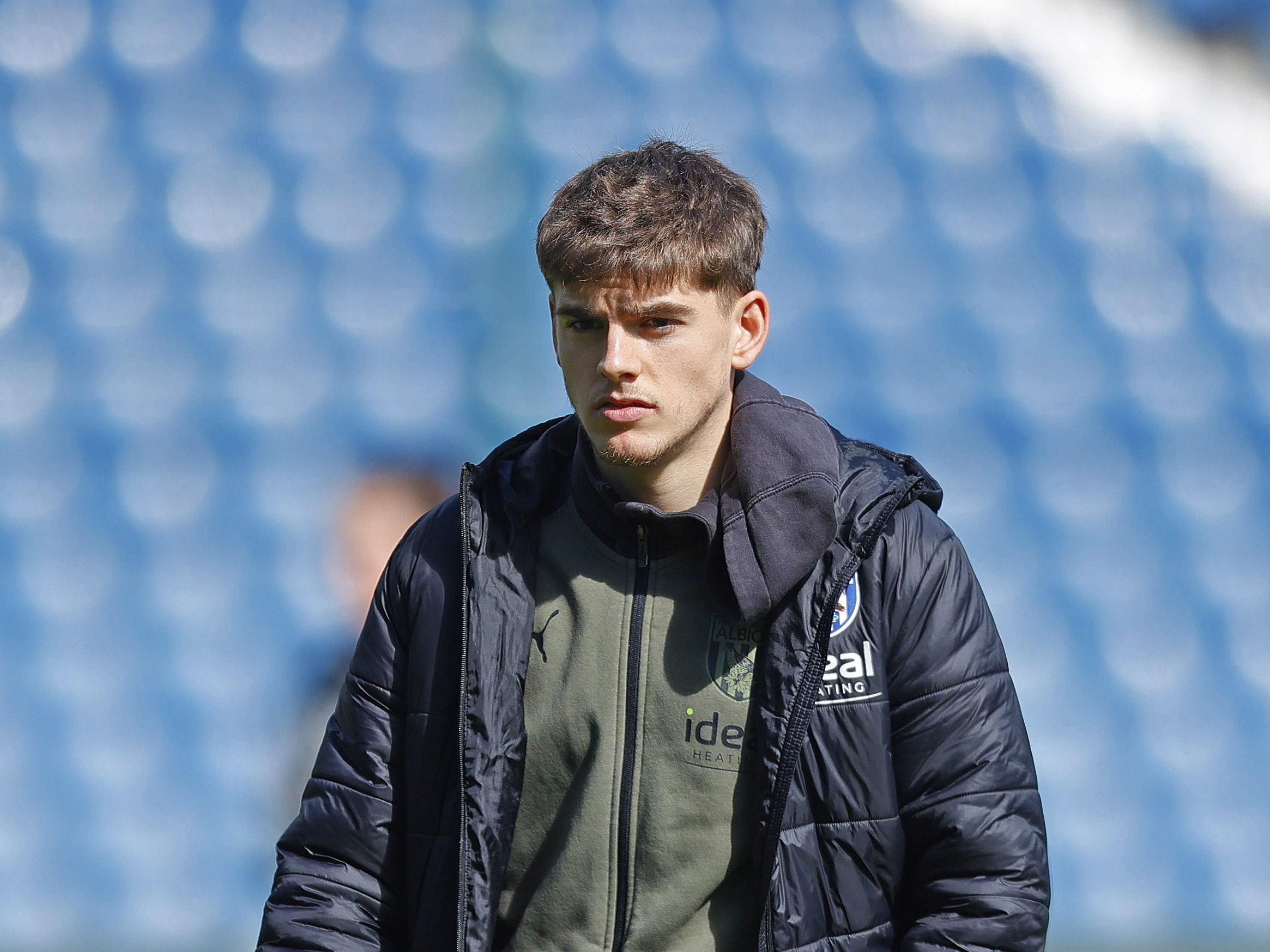 Tom Fellows in a club tracksuit and coat at The Hawthorns before a game