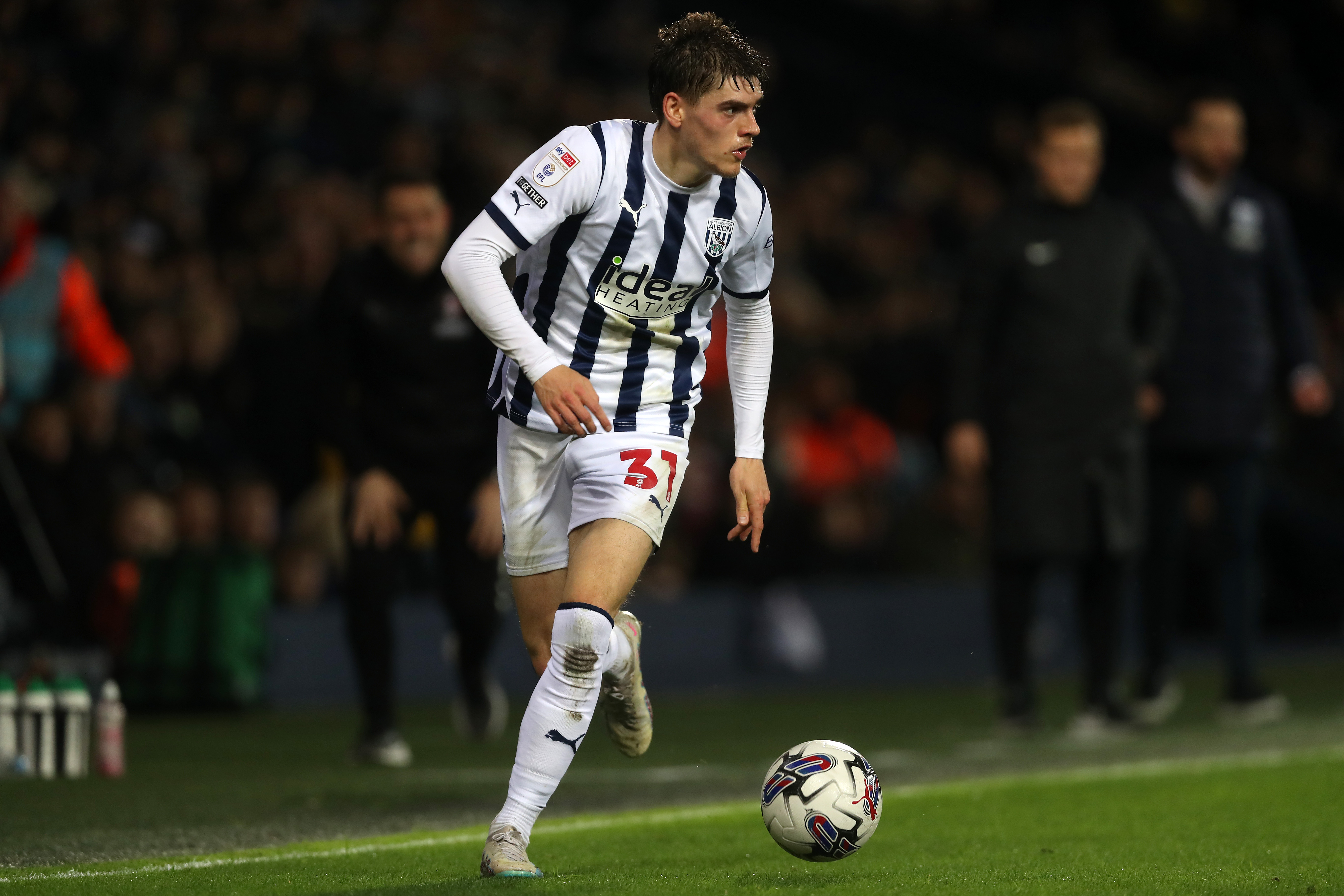 Tom Fellows running with the ball wearing the home Albion kit at The Hawthorns