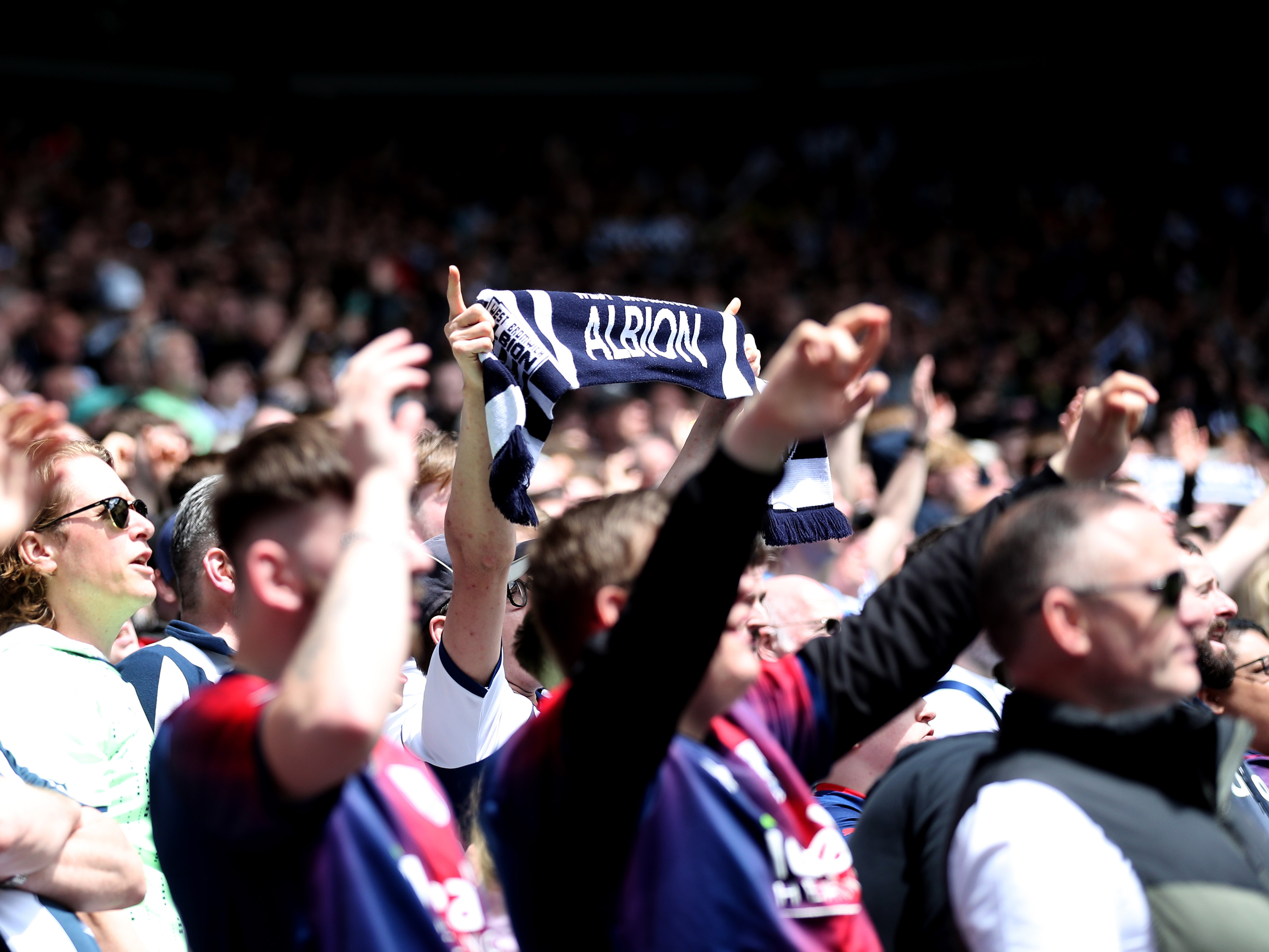 Albion fans holding up an Albion scarf at a match